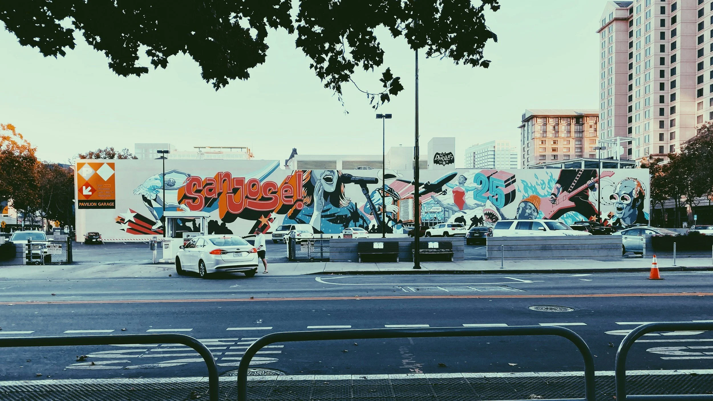 A city street with a graffiti-covered wall and parked cars