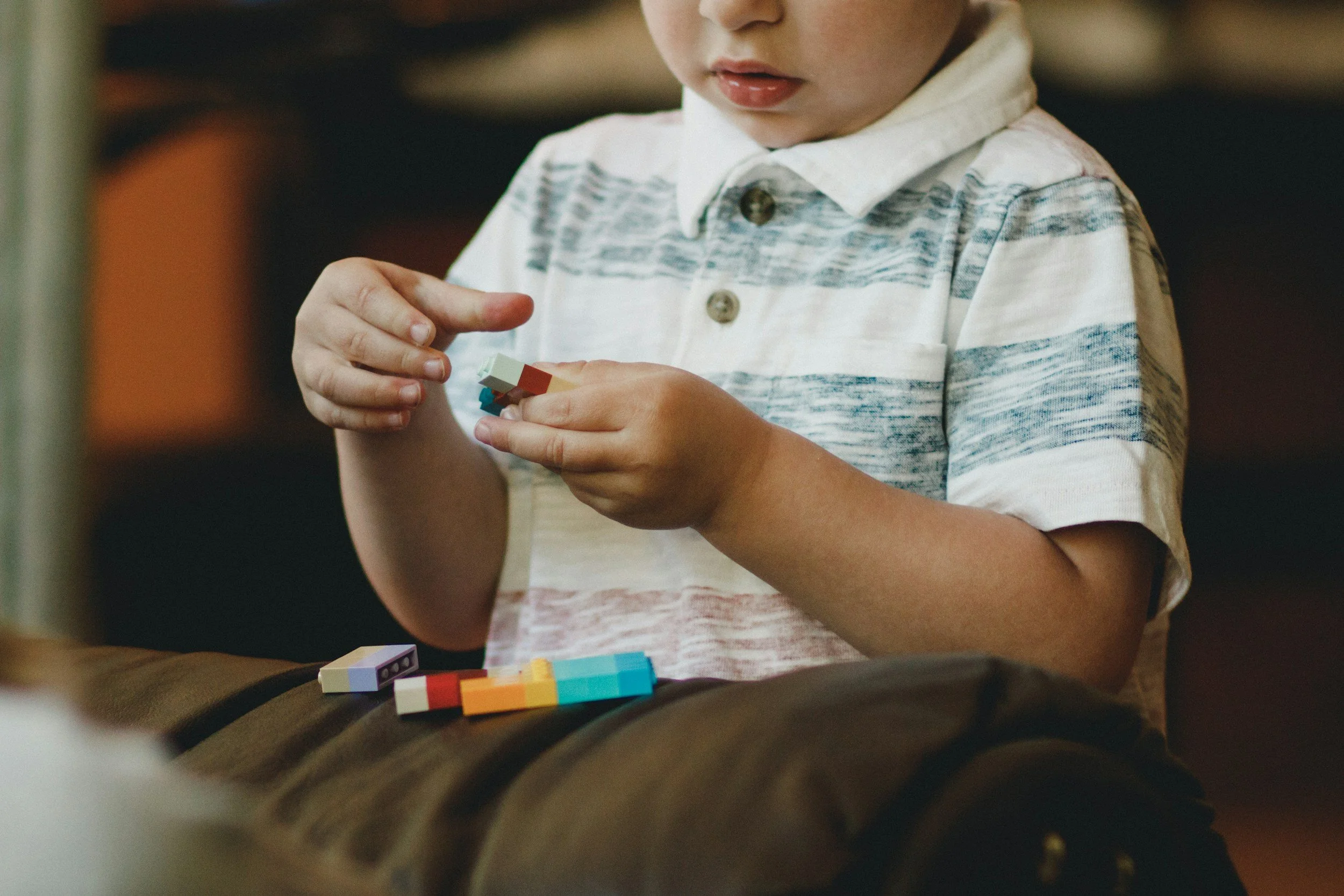 A young boy sitting and building with small plastic bricks