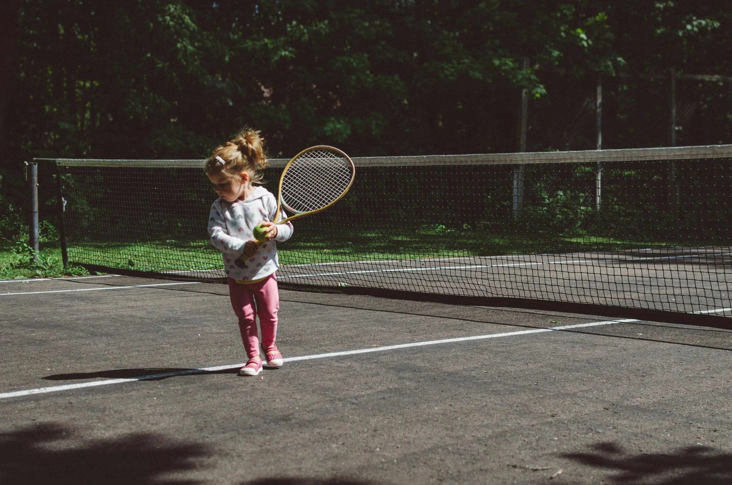 A young child standing on a tennis court holding a racket