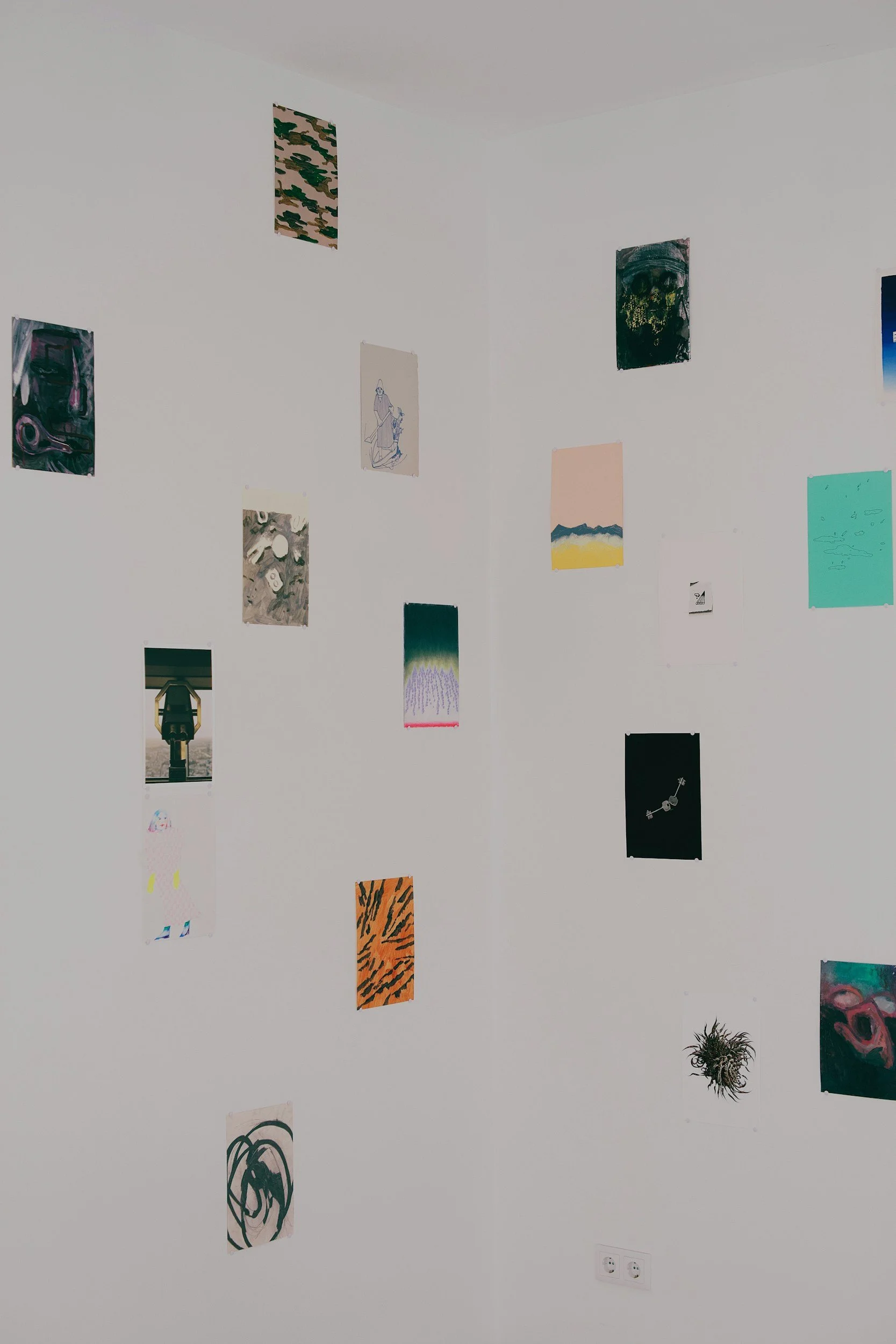 Small photographs and cards taped in a loose grid on a white wall