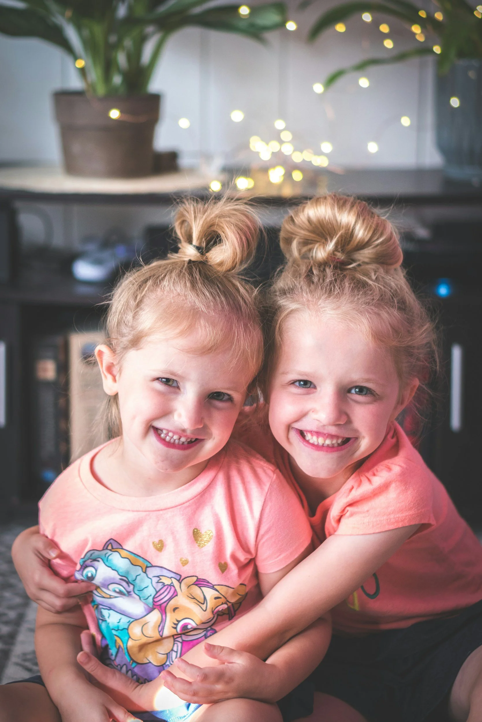 Two young sisters hugging, one holding a bag of candy