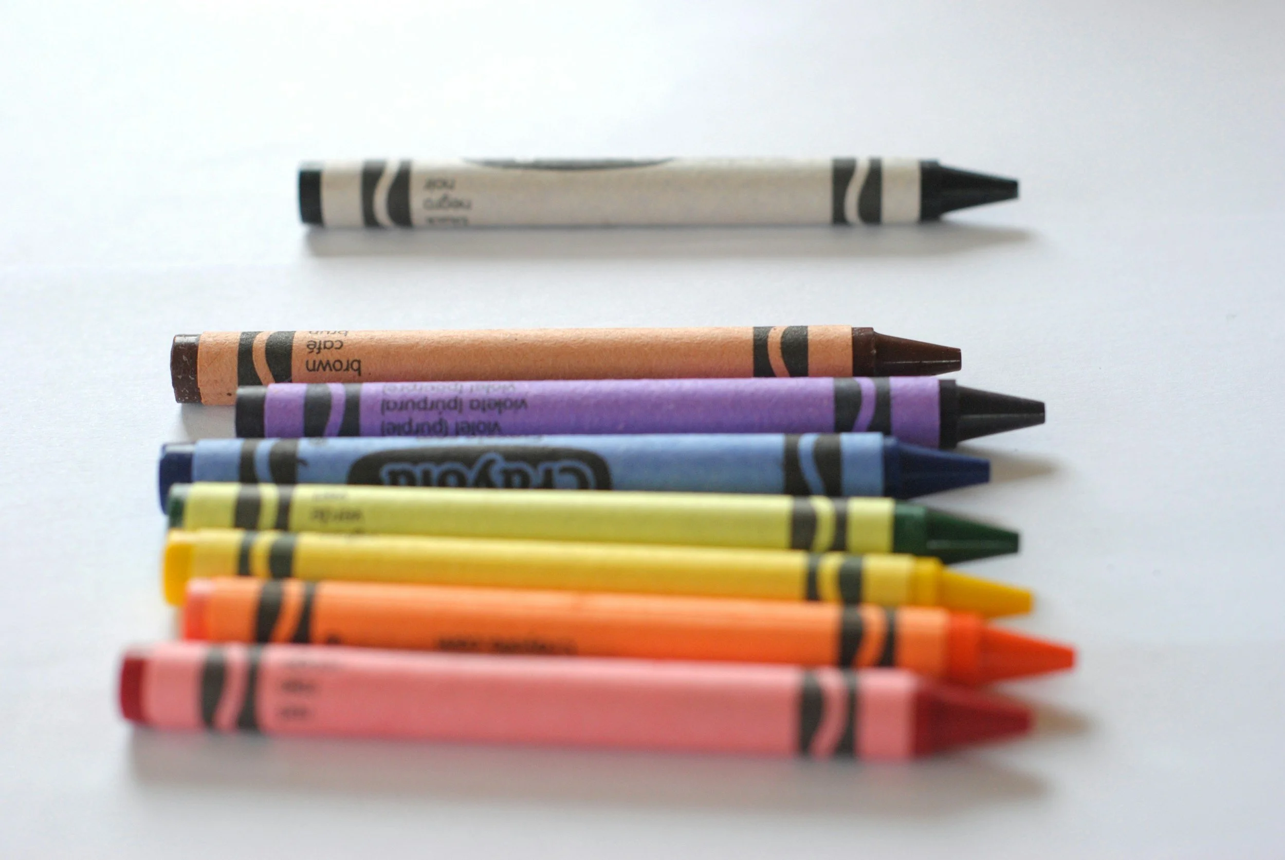 A row of crayons lined up on a white surface