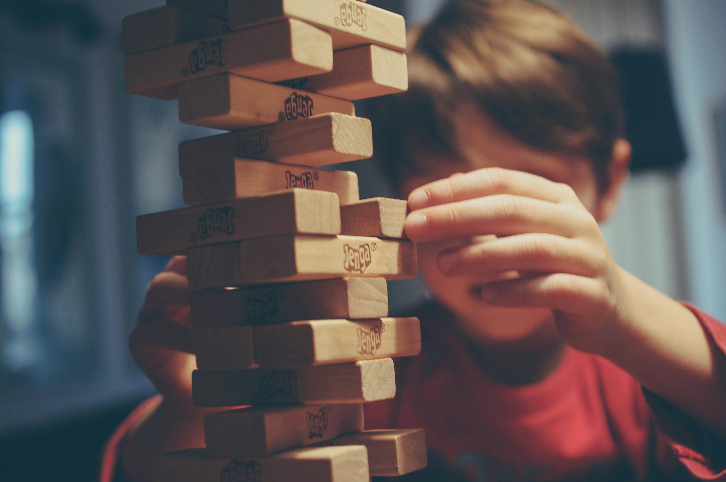 A child carefully pulling a block out of a wooden tower