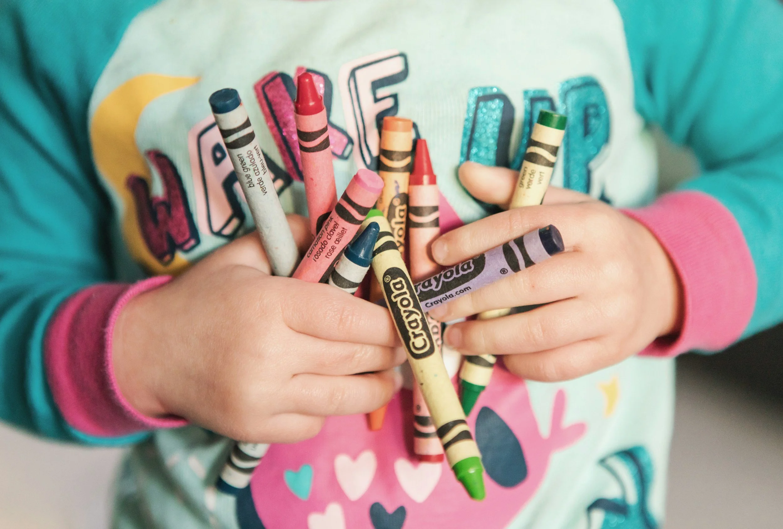 A child holding a big armful of crayons