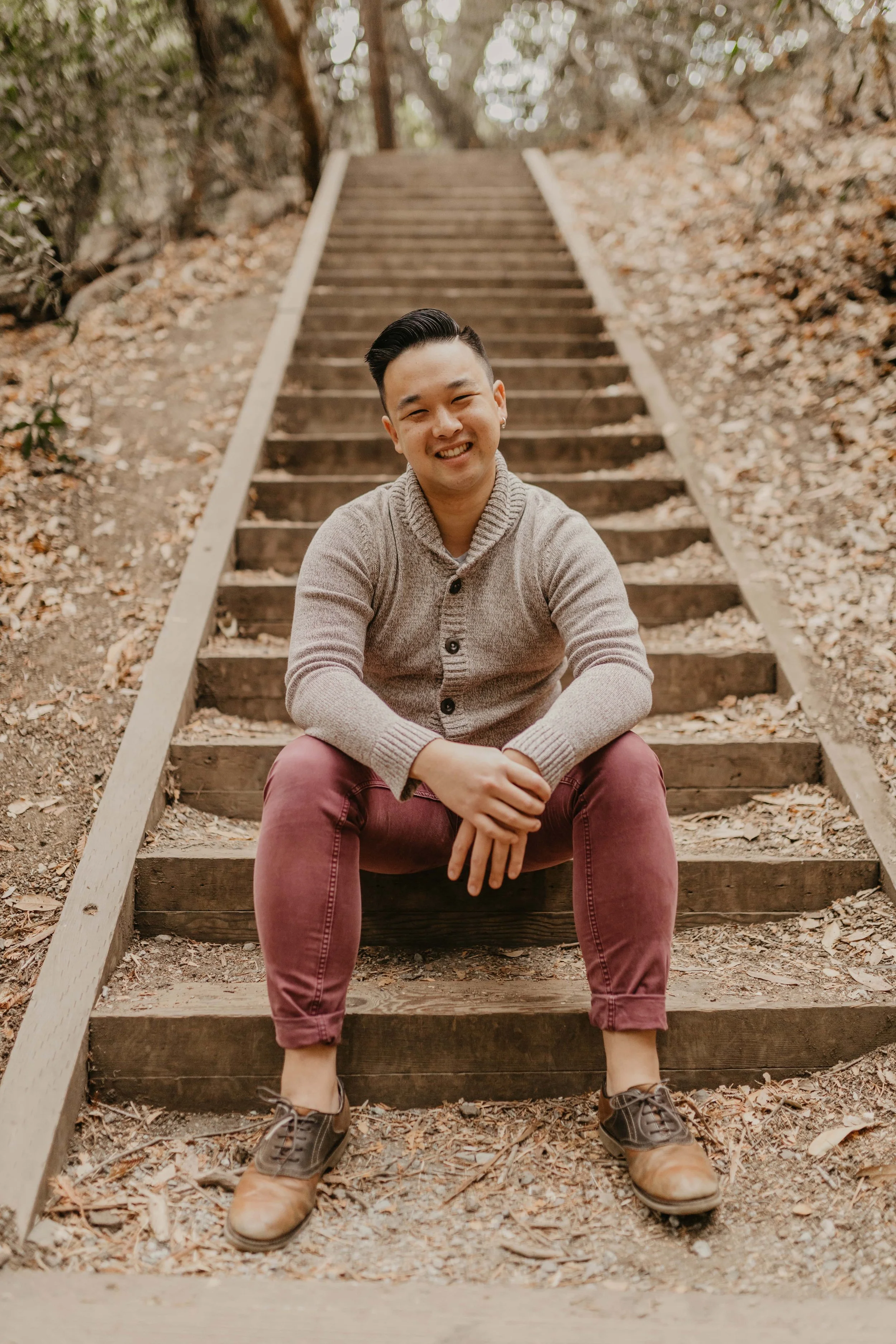 Alex Ly sitting on wooden steps in a wooded park