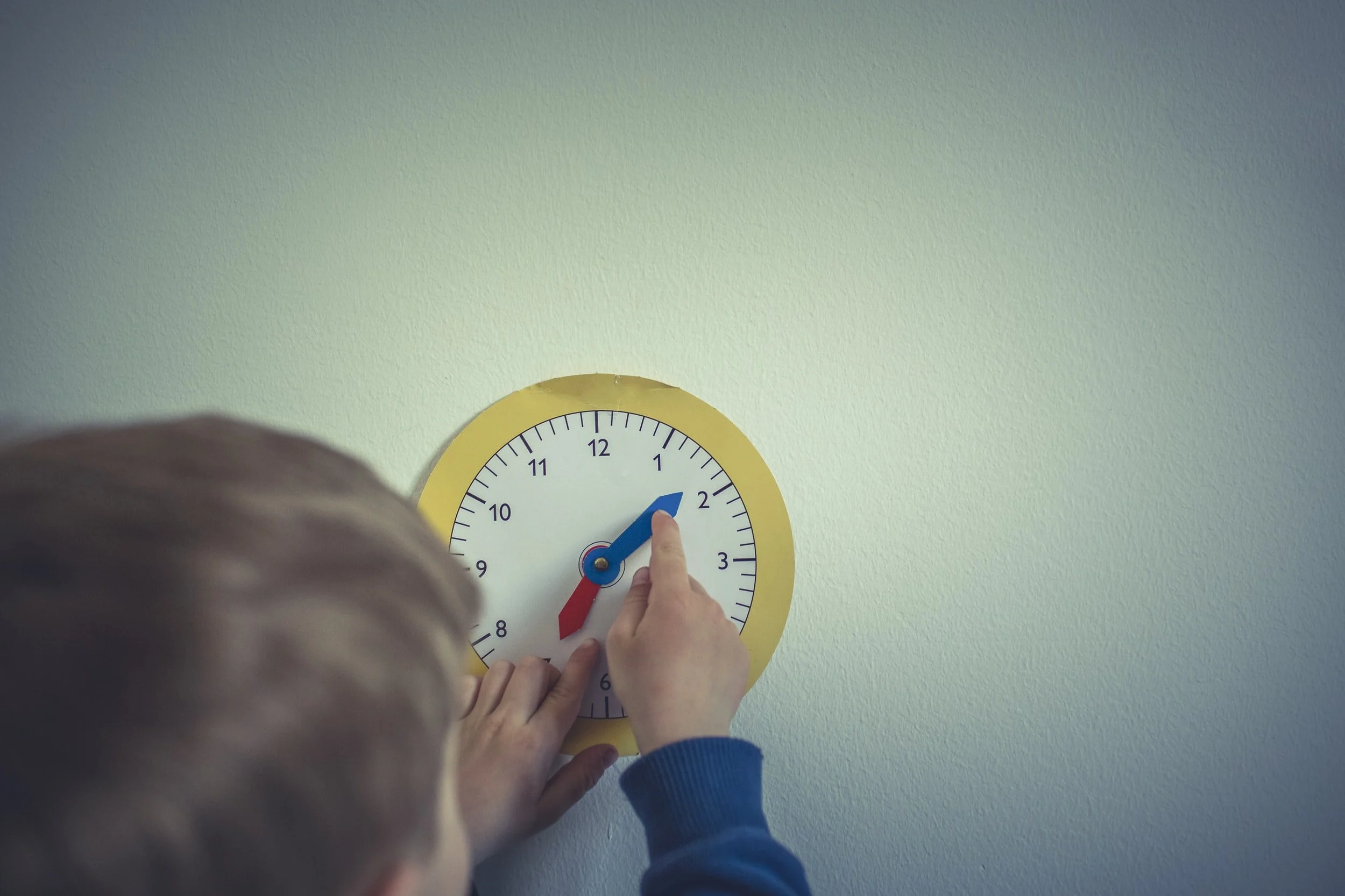 A child drawing a clock face on paper with a pen
