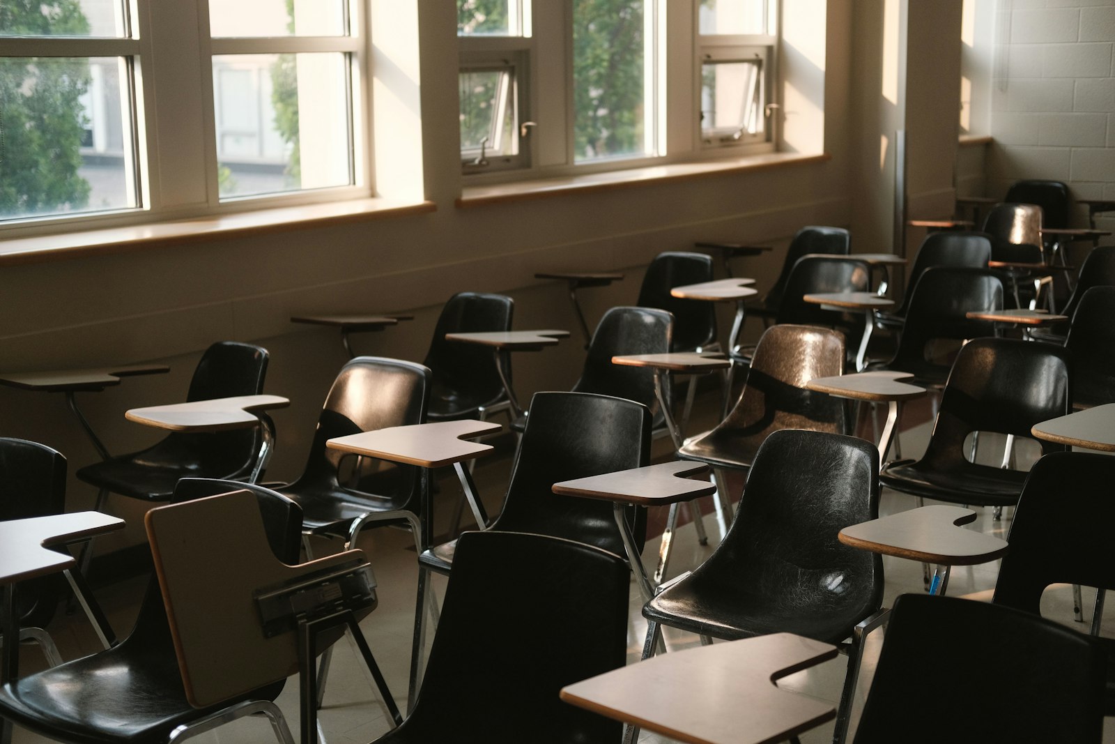 Empty classroom desks by tall windows at the start of the school year