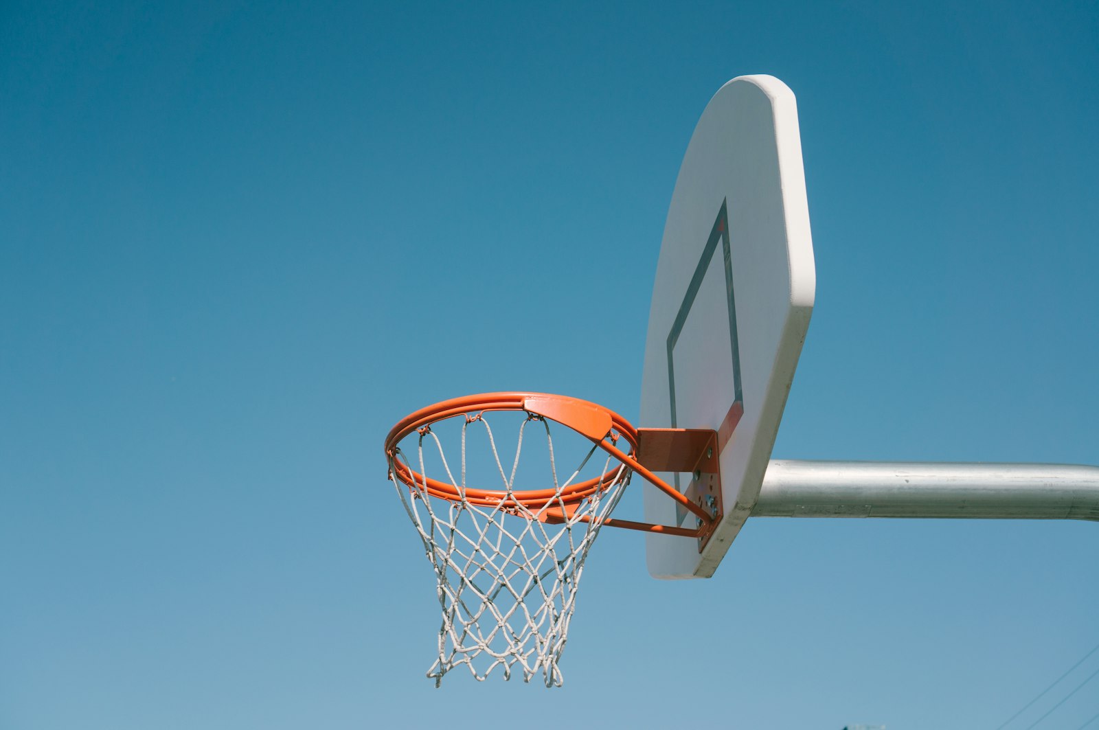 A school basketball hoop against a blue sky, recess and friendships