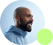 Profile of a bald man with a beard wearing a blue button-up shirt smiling, with a smaller green circle overlapping the lower right edge.