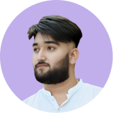 Portrait of a young man with a beard and styled dark hair, wearing a white shirt, looking slightly to the side.