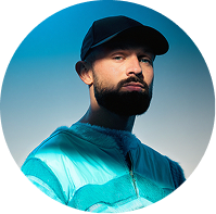 Portrait of a bearded man wearing a black cap and teal jacket.