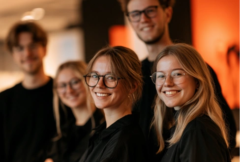 Smiling team of four colleagues posing together in a warmly lit office.
