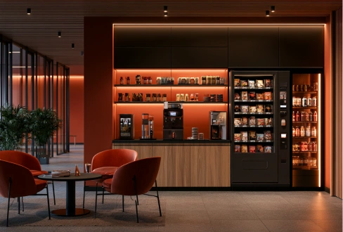 Contemporary office refreshment area with vending machines, coffee facilities, and lounge seating in warm lighting.
