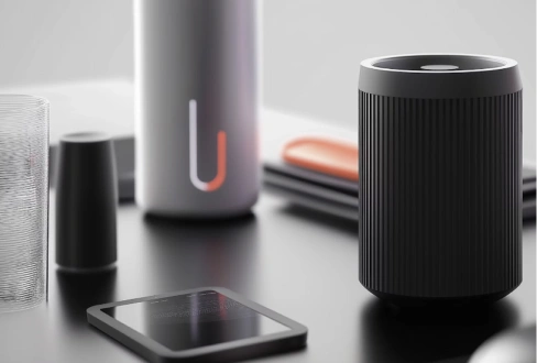 Modern smart speaker and connected electronic devices arranged on a sleek black tabletop.
