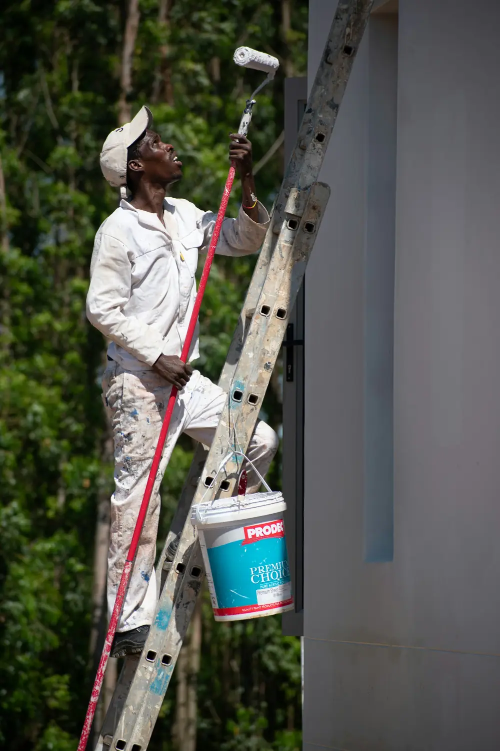 House painter on a ladder painting the outside of a home