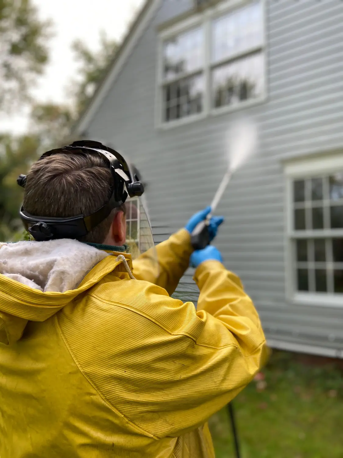 Worker pressure washing the siding of a house