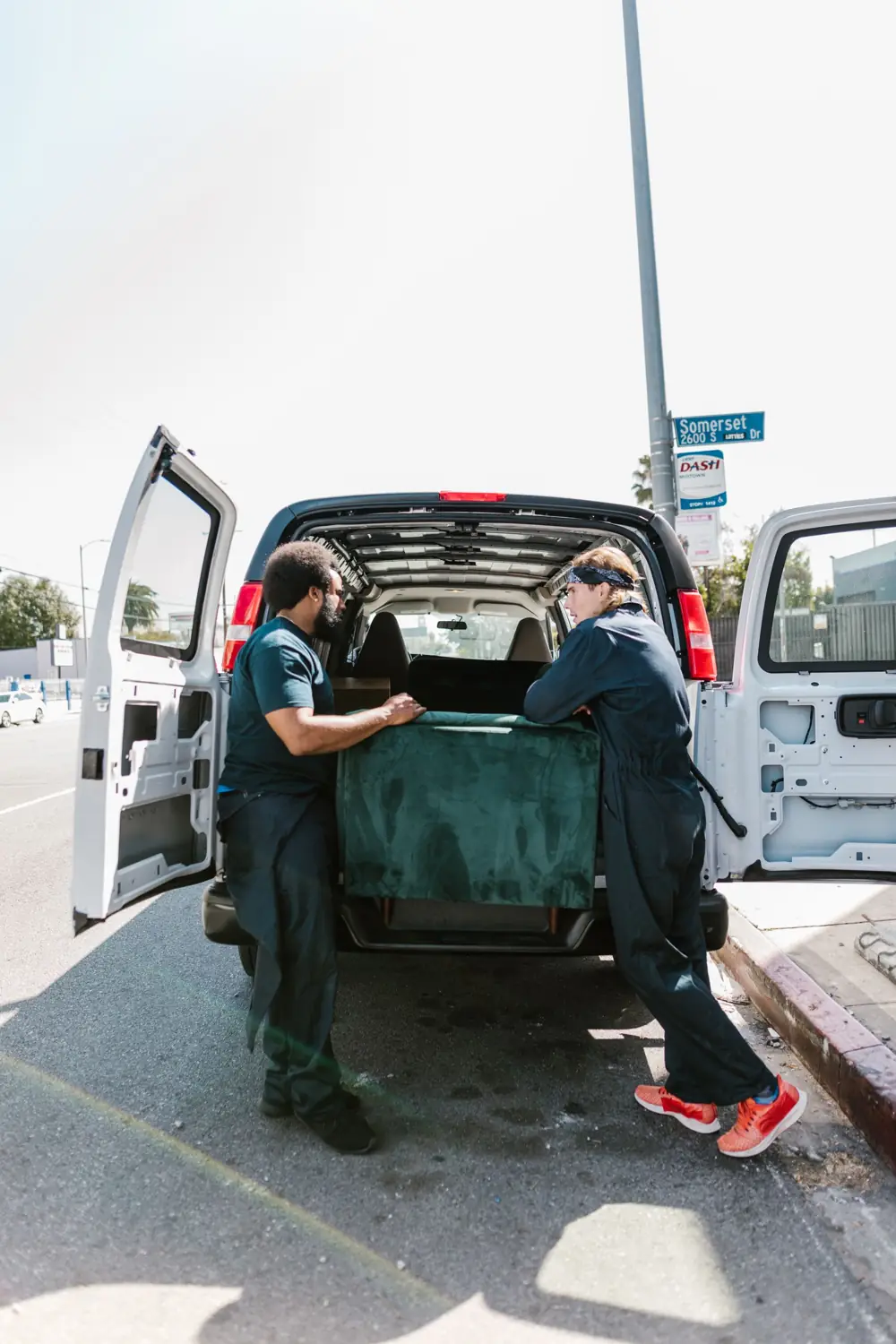 Two movers loading a couch into a moving van