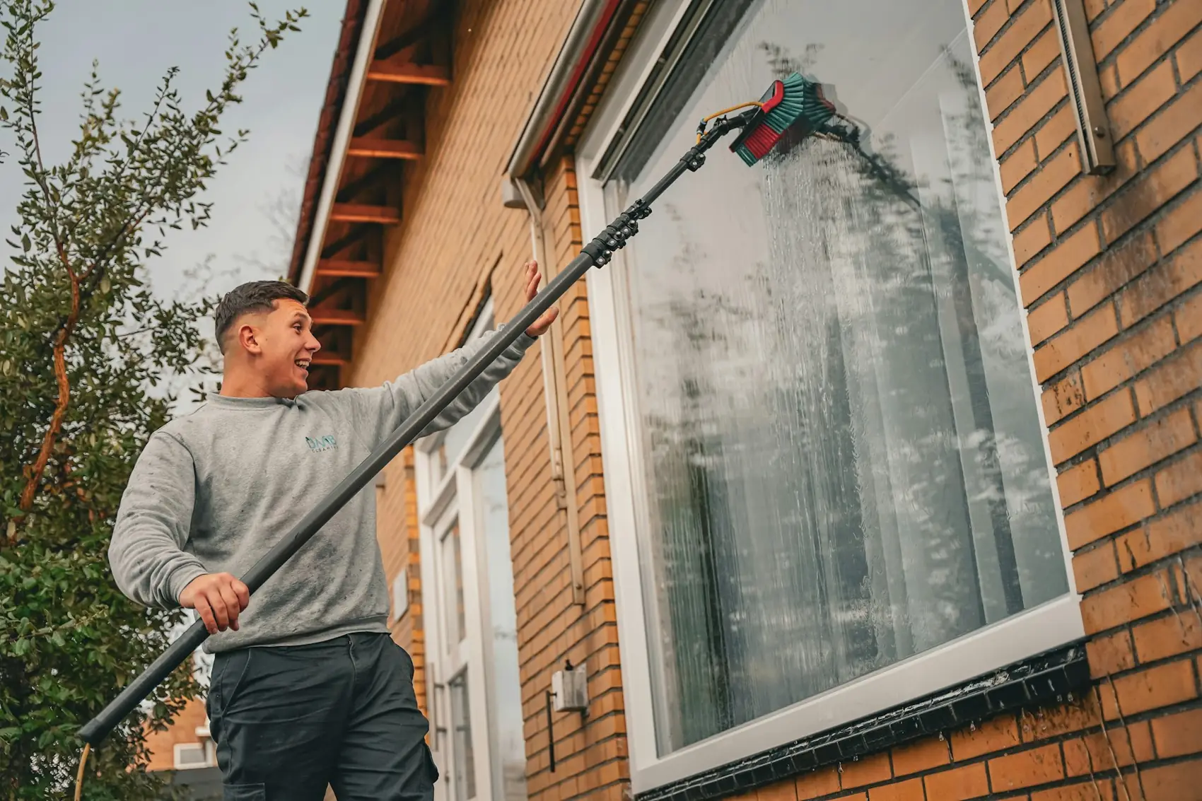 Window cleaner using a water fed pole on a brick house