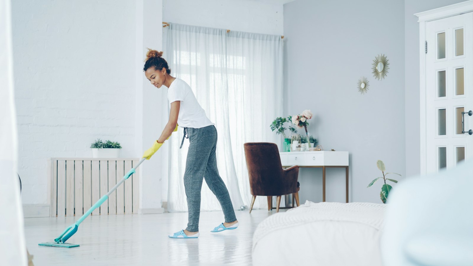 House cleaner mopping the floor of a bright living room