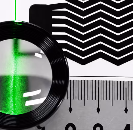 Magnifying glass with green light inspecting a black and white acetate plate pattern and ruler.