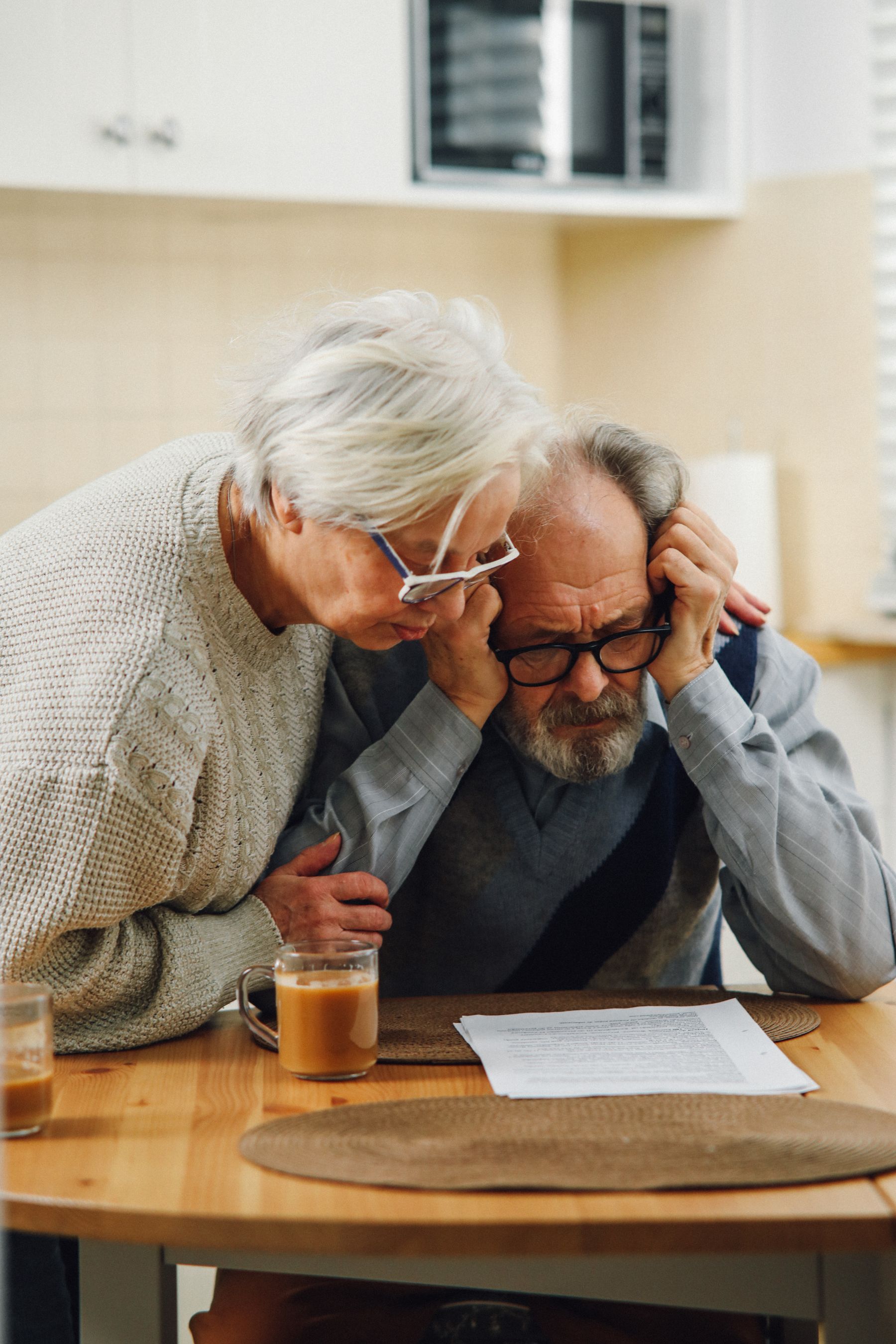 Older homeowners carefully reviewing paperwork together at a table