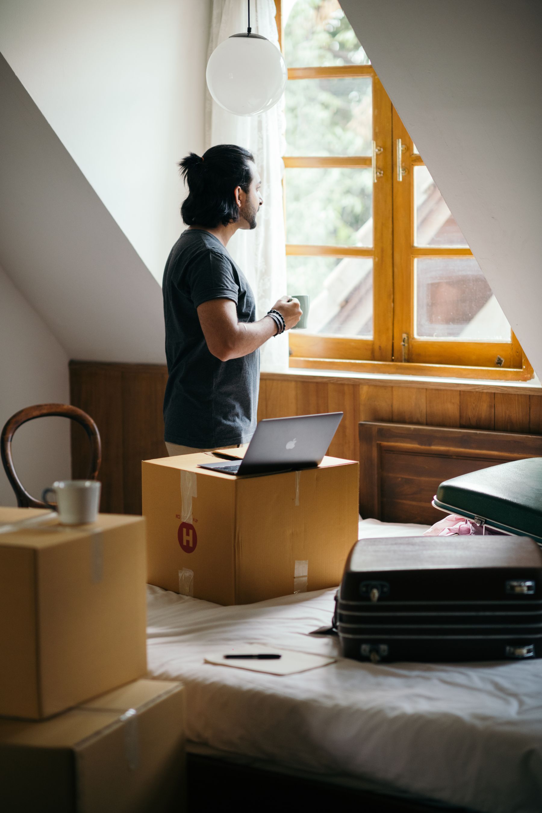 Person pausing beside a residential window while considering a major home decision