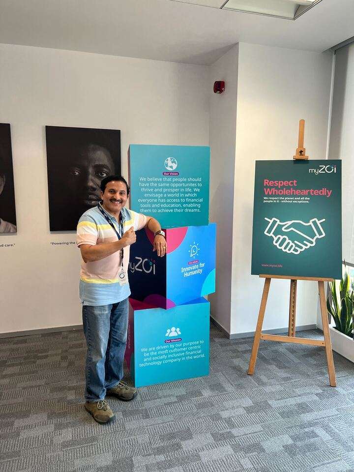 Man giving a thumbs up beside myZoi vision and mission displays in an office