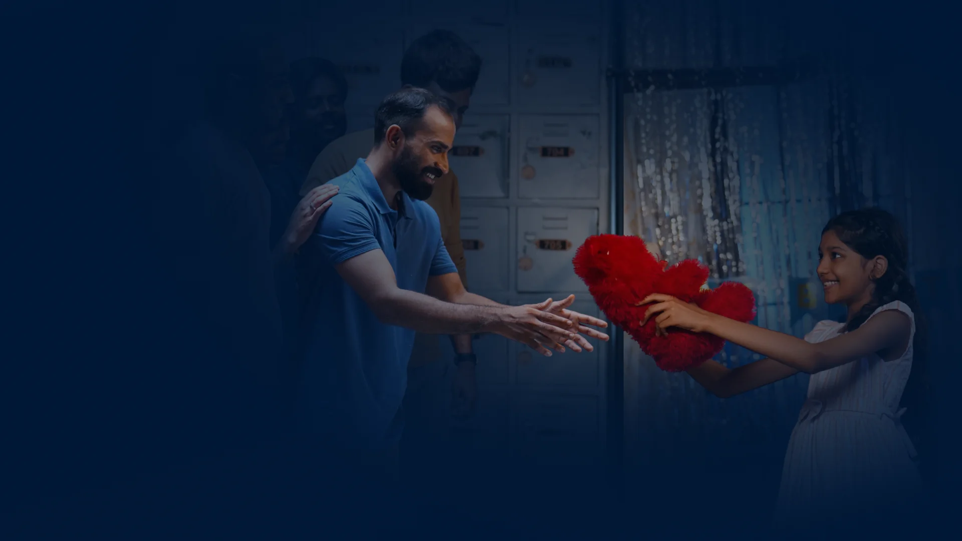 Father handing a red teddy bear to his smiling daughter
