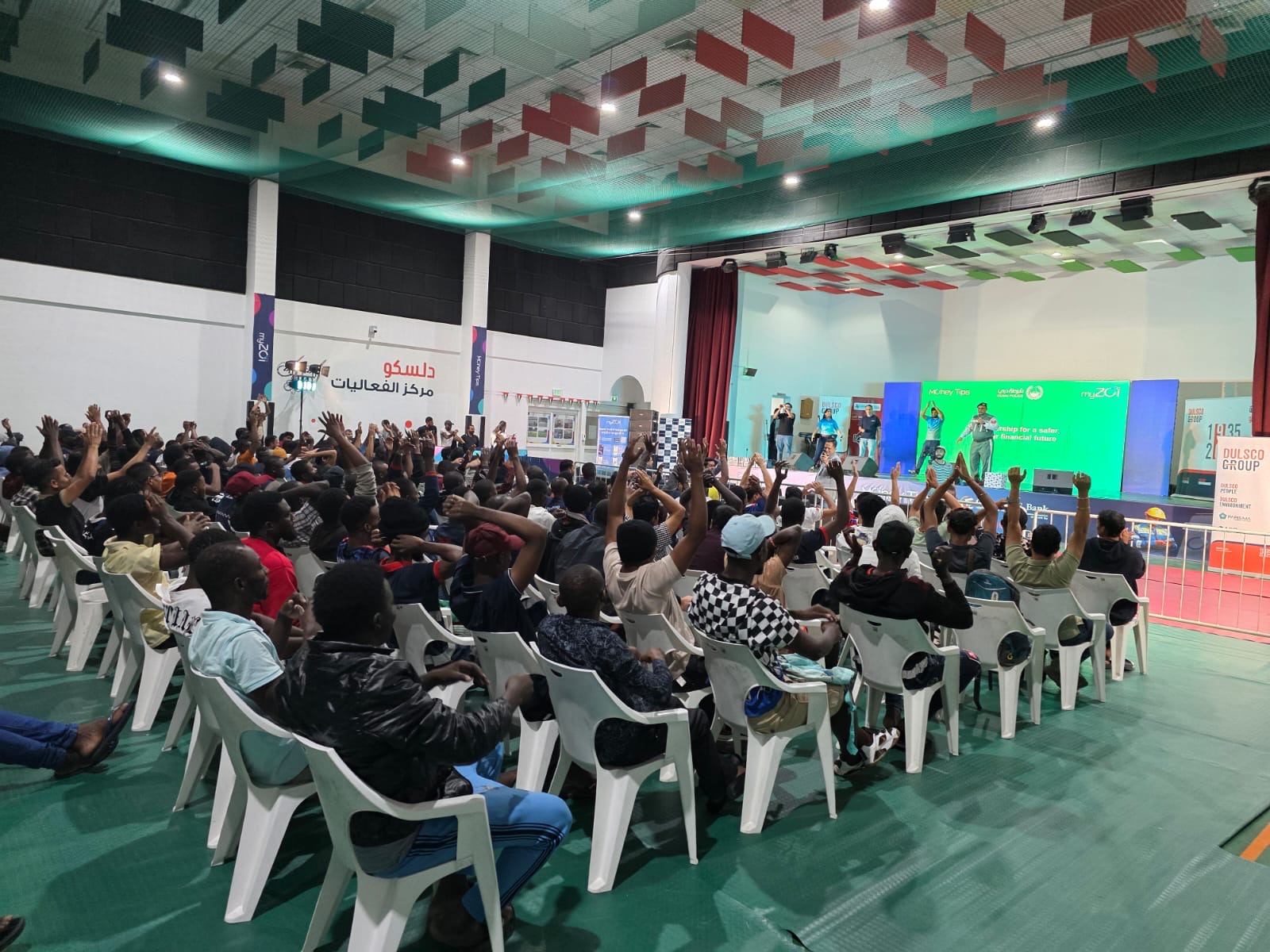 Workers raising their hands at a myZoi community event in a large hall
