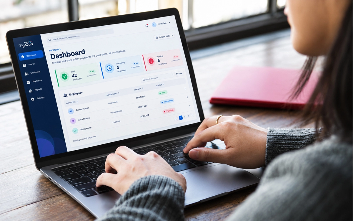 Woman using the myZoi payroll dashboard with employee payment statuses on a laptop