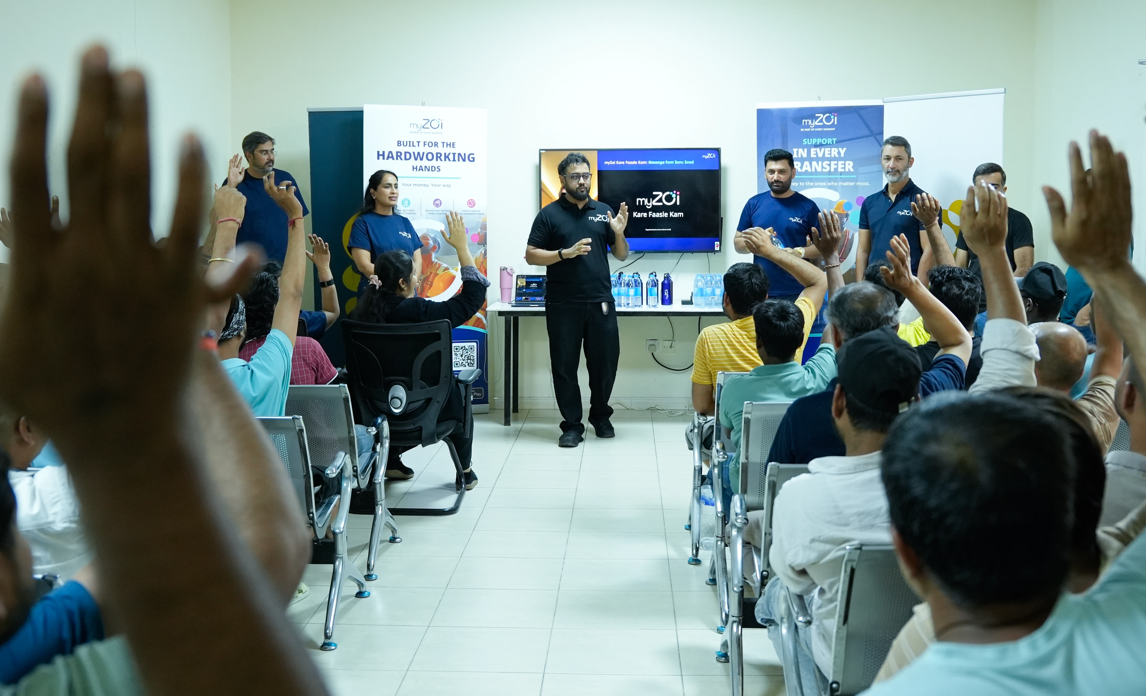 myZoi team presenting to workers raising their hands in a training room