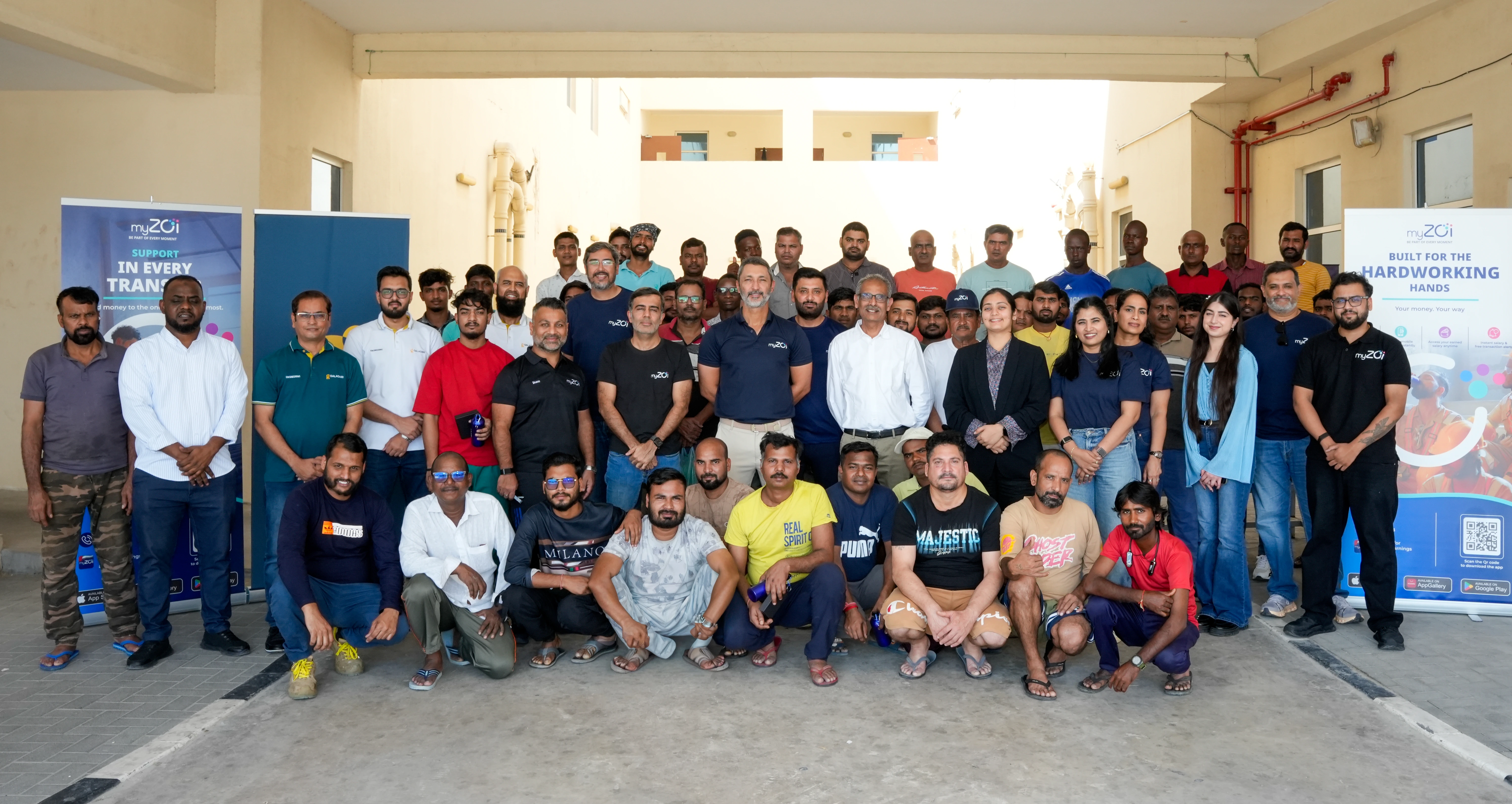 Large group of workers and myZoi team members posing outdoors at a myZoi community event