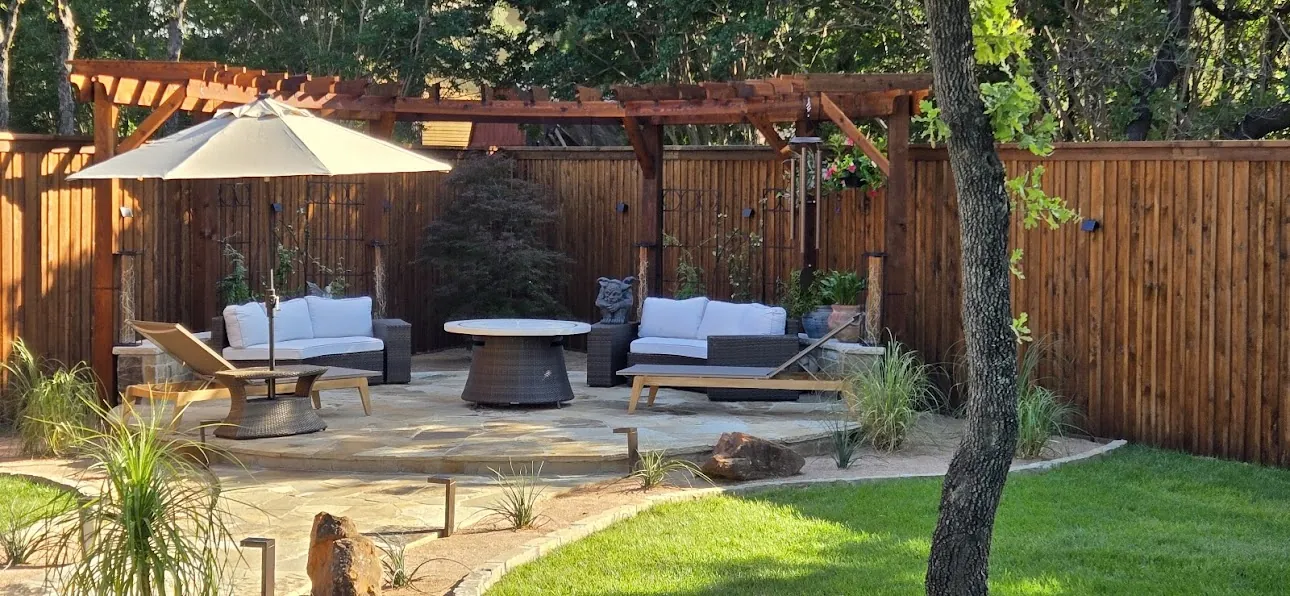 Intimate backyard seating area with flagstone, pergola, lawn, and mature oak trees
