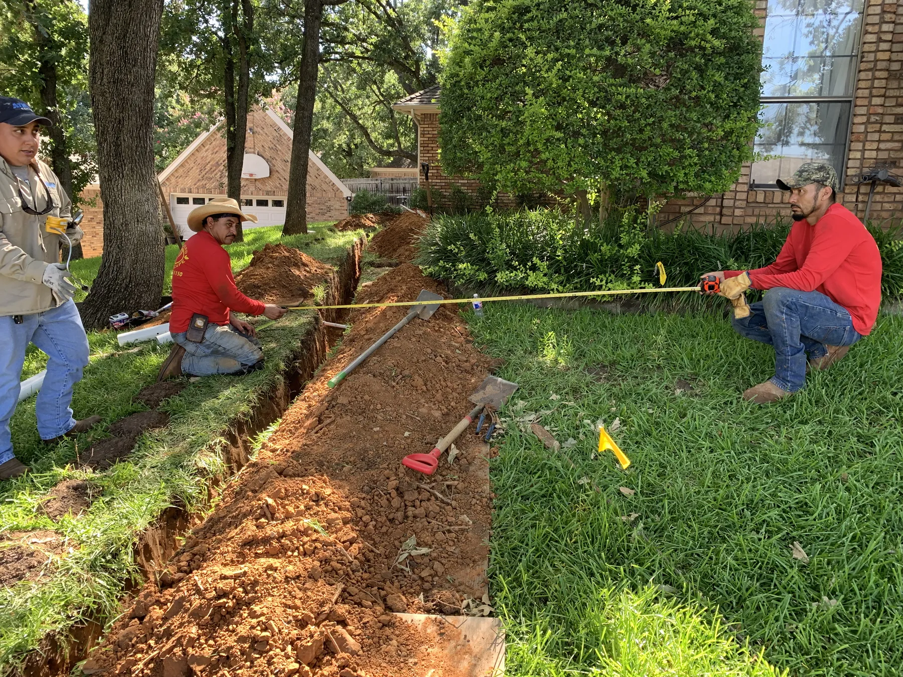 Pinckard Landscape crew measuring and installing drainage at a North Texas home