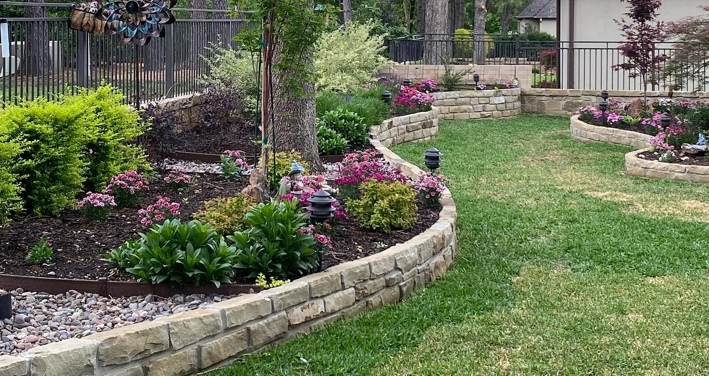 Terraced natural stone borders with lawn, shrubs, and planting beds in a North Texas backyard