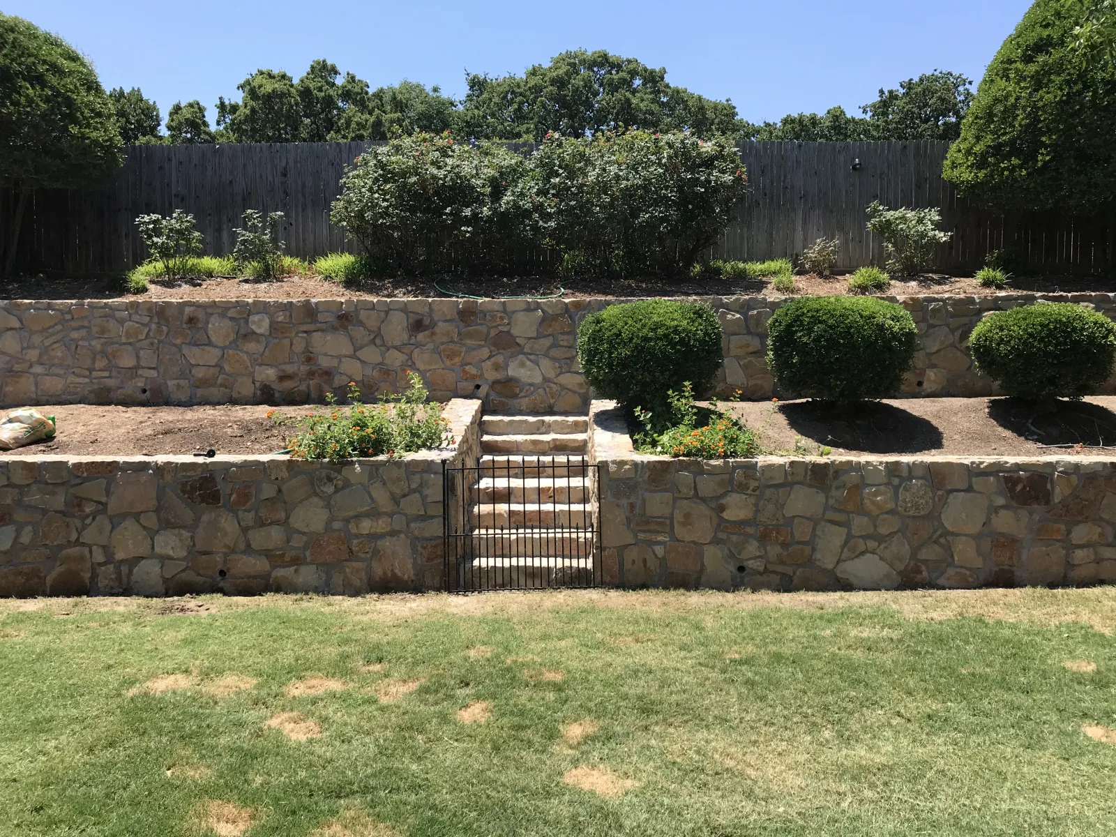 Terraced natural stone retaining walls supporting a landscaped slope