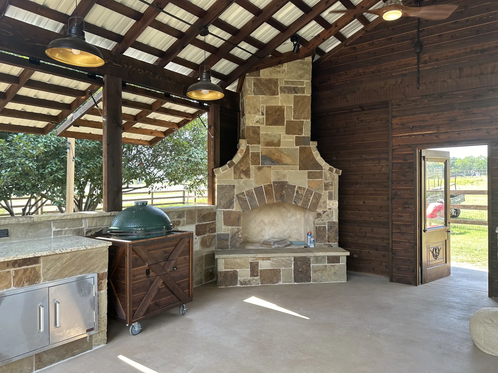 Covered outdoor kitchen with a built-in grill and stone fireplace
