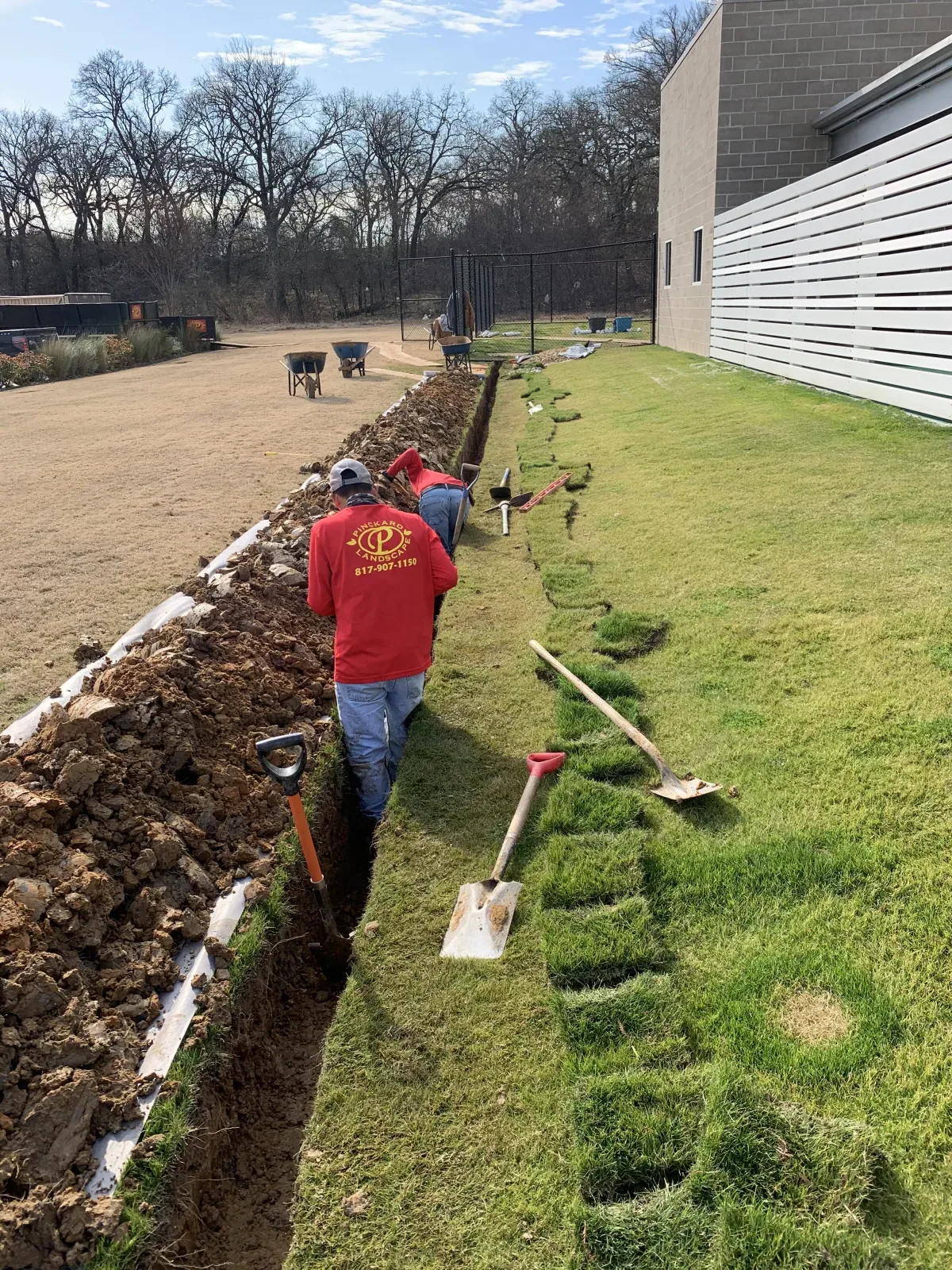 Pinckard Landscape crew installing an underground drainage pipe in a residential yard