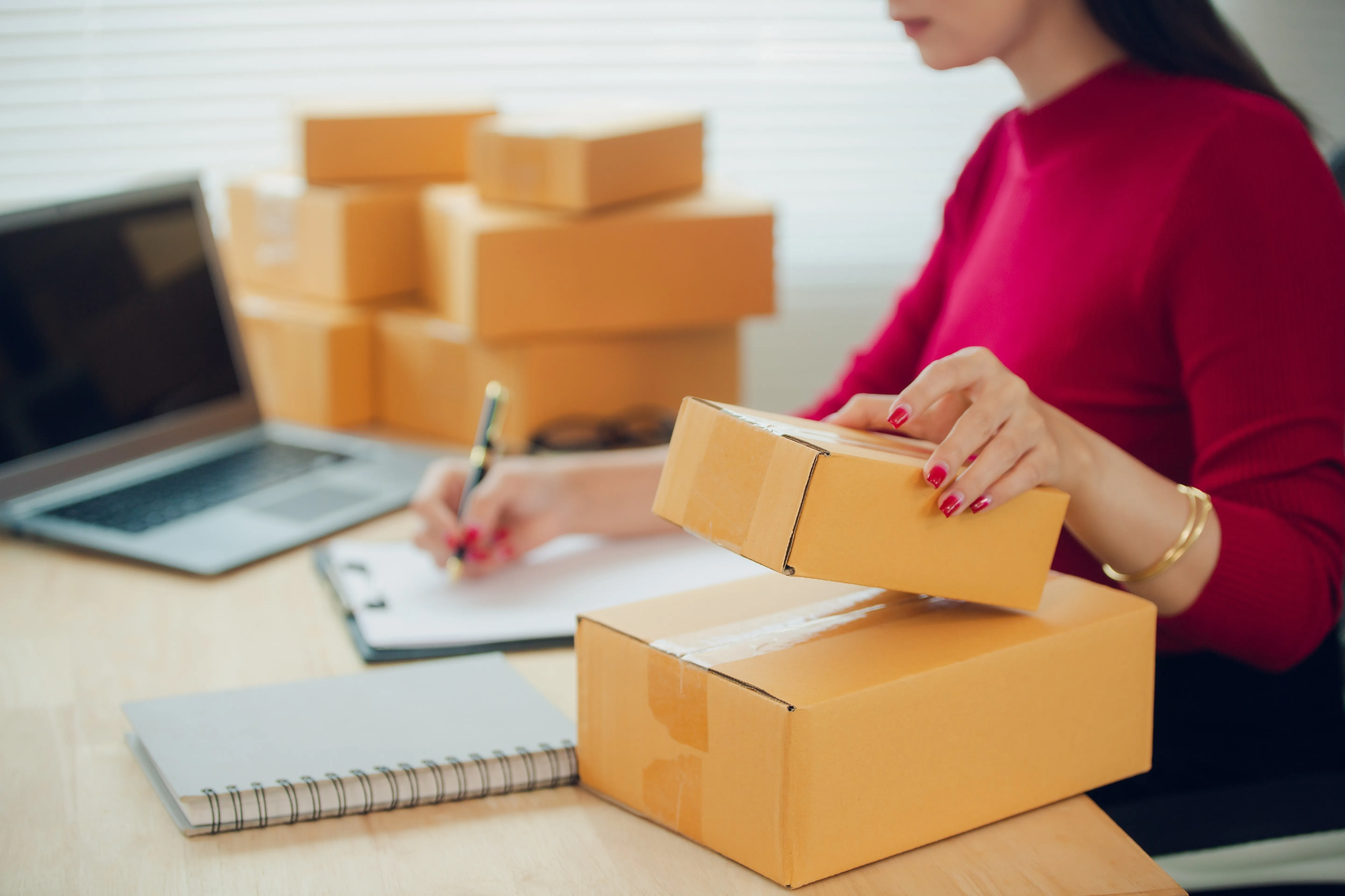 Ecommerce order packing with product boxes and a laptop.