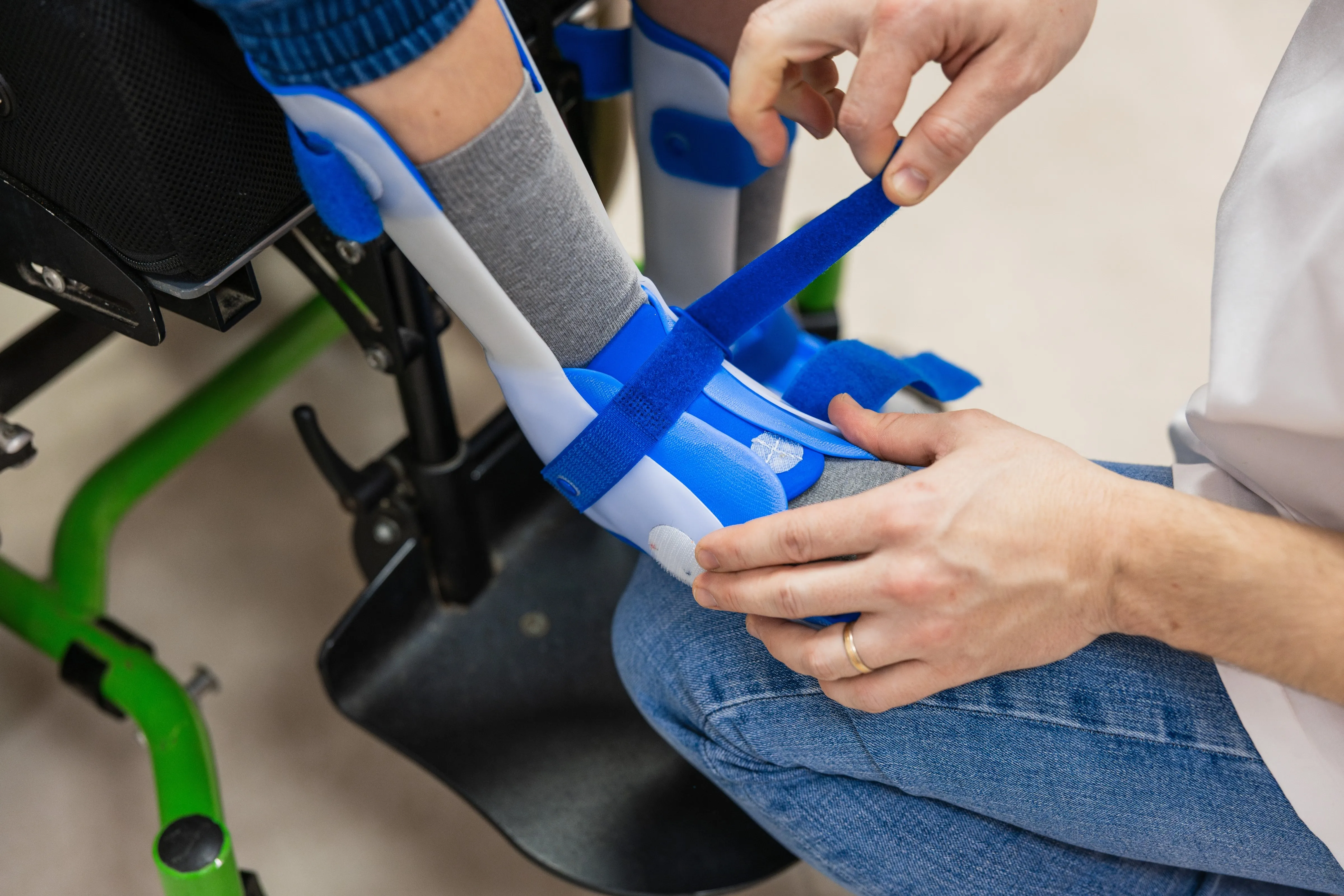 Clinician adjusting an orthopedic leg brace for a wheelchair user.