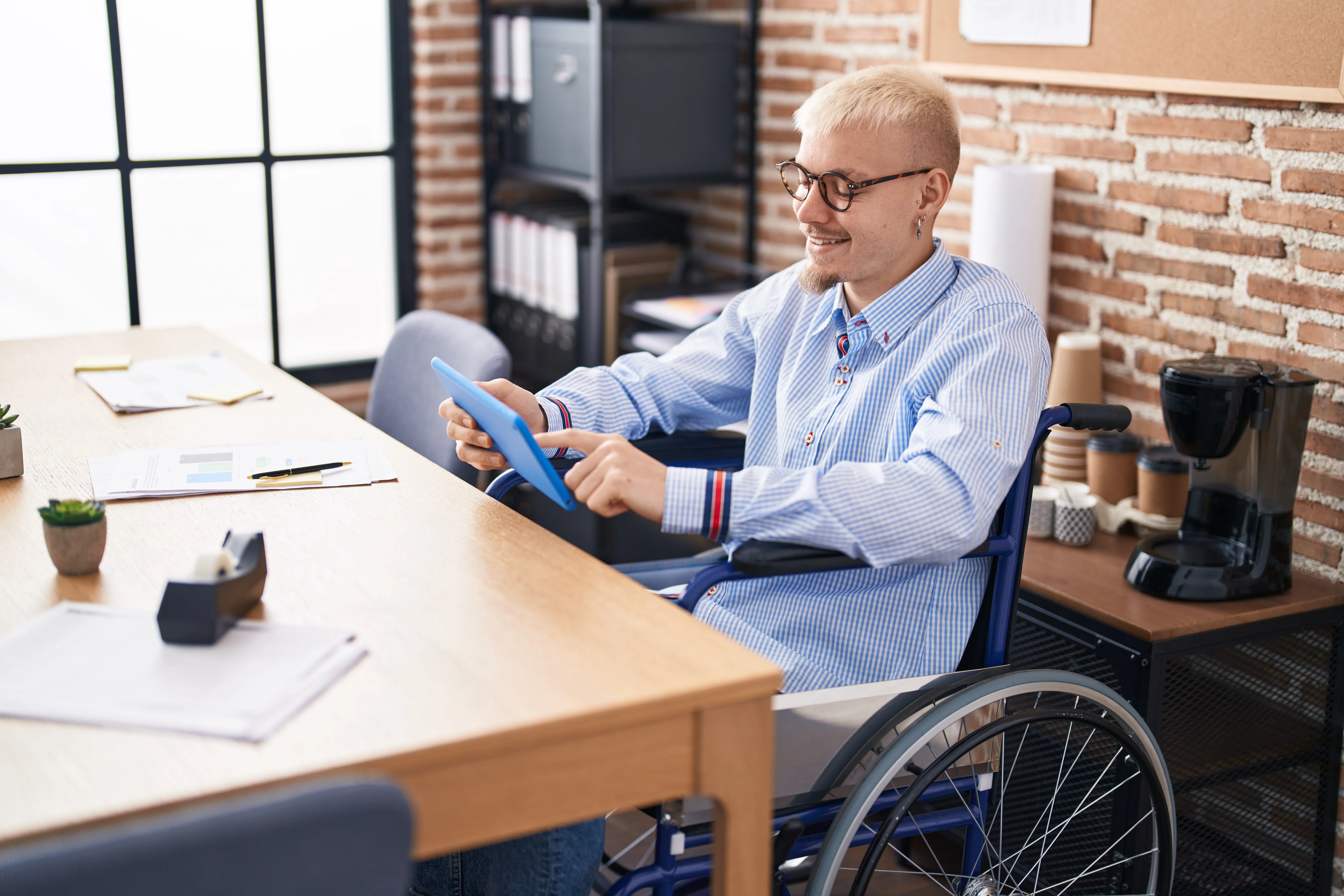 Wheelchair user working with a tablet in a modern office.