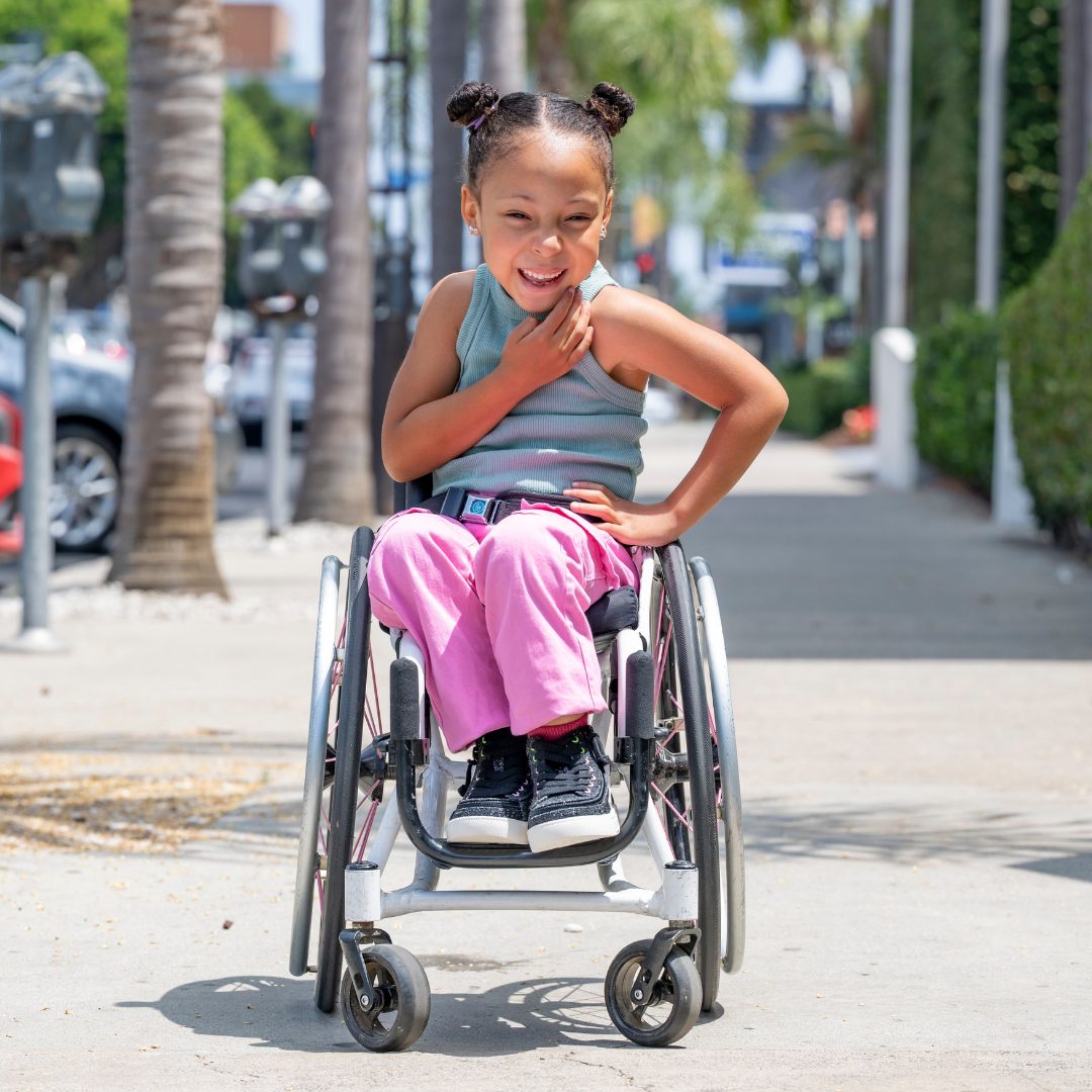 Child seated in a wheelchair wearing black BILLY sneakers