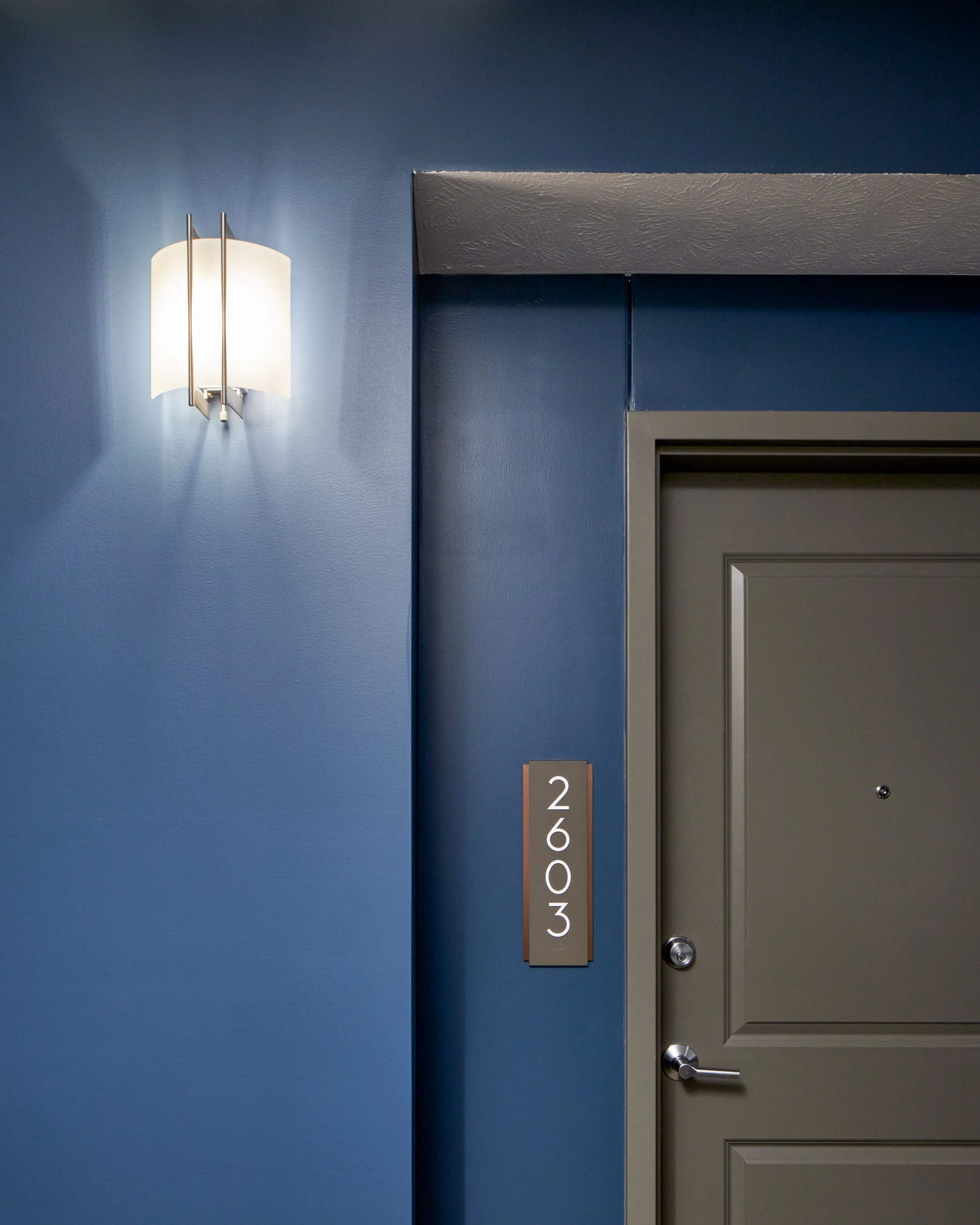 Apartment entry door with a wall sconce against a navy accent wall