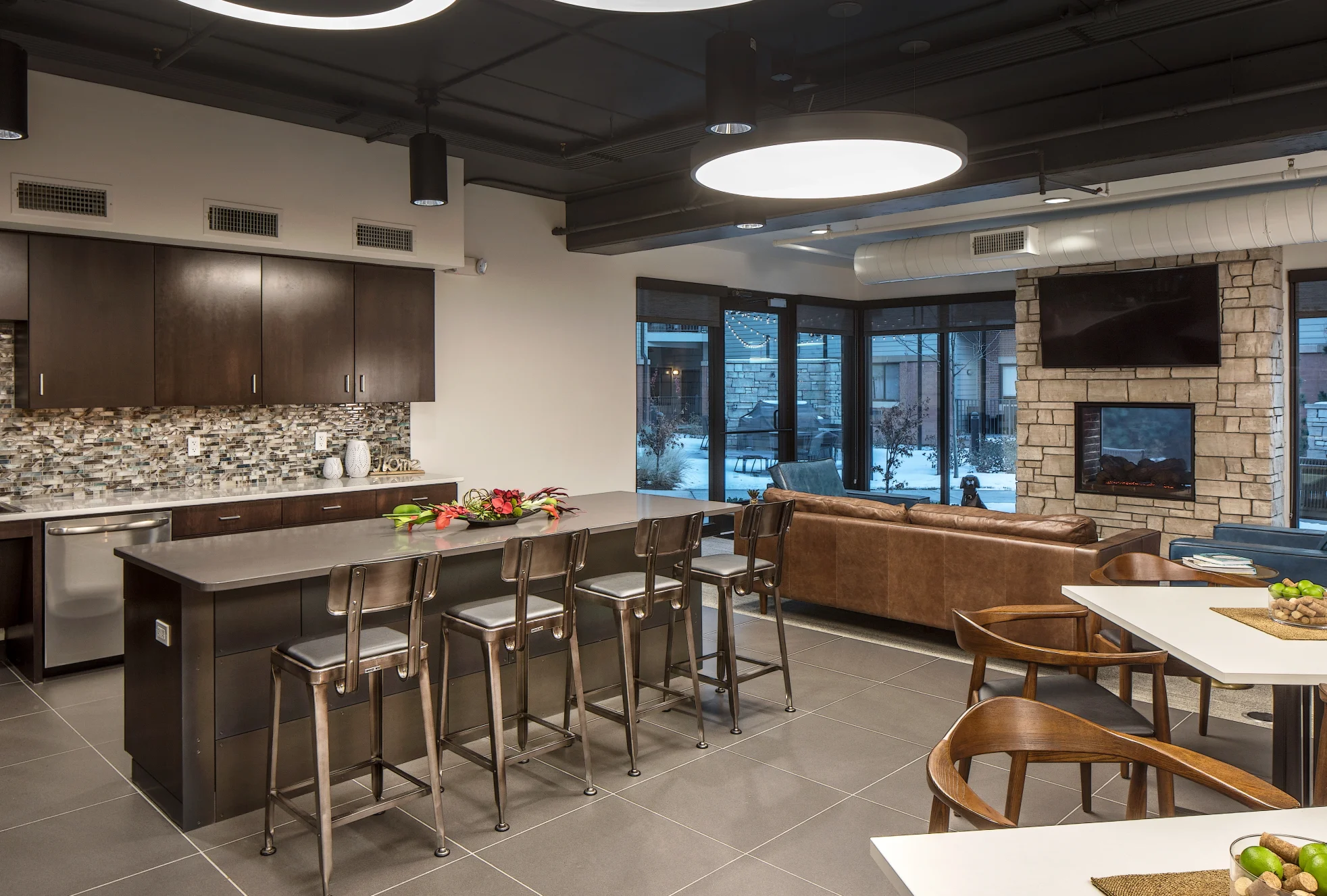 Resident clubroom at The Conrad with a kitchen island, bar stools, lounge seating and a stone fireplace