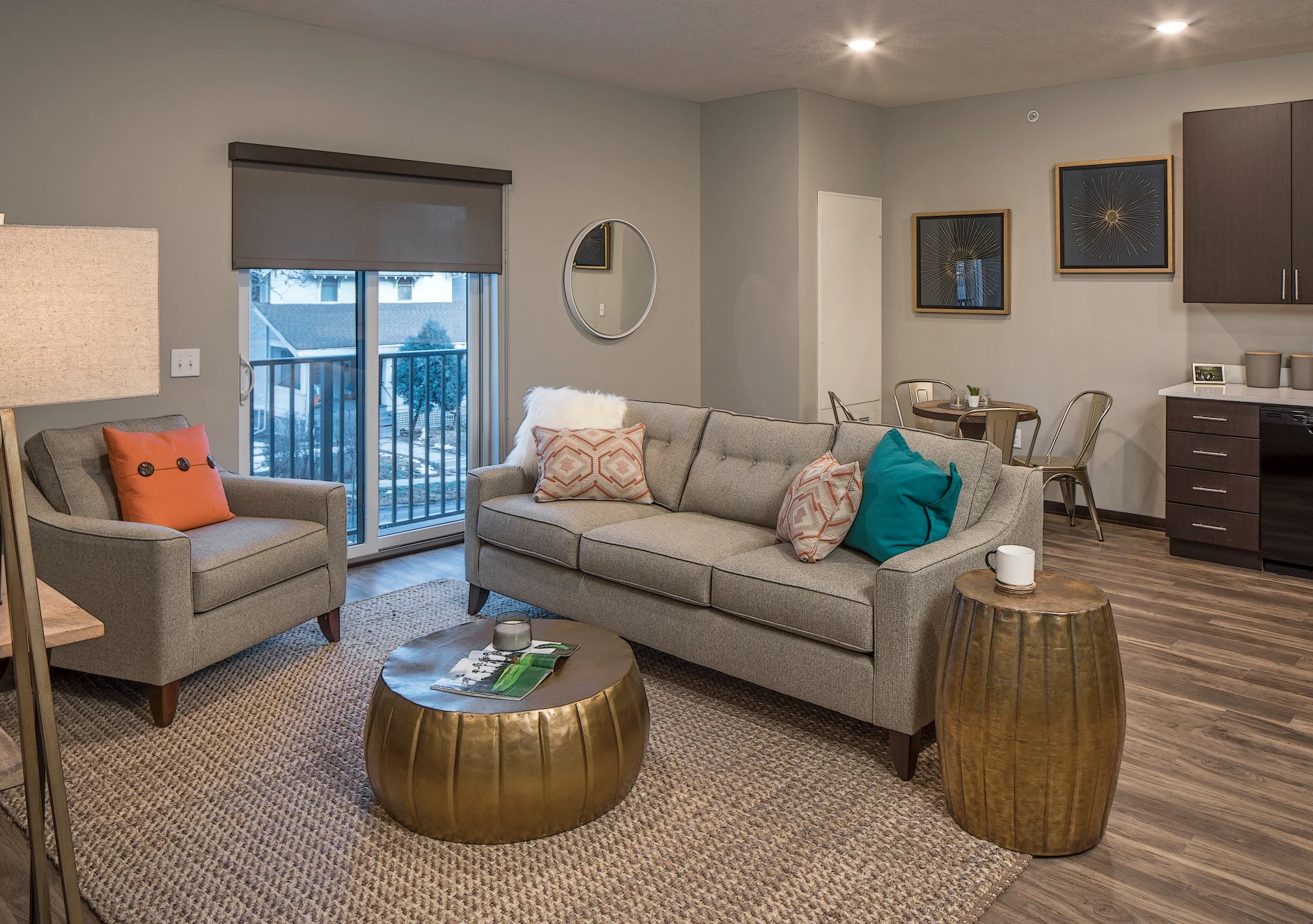 Model apartment living room with a gray sofa, gold side tables and a patio door