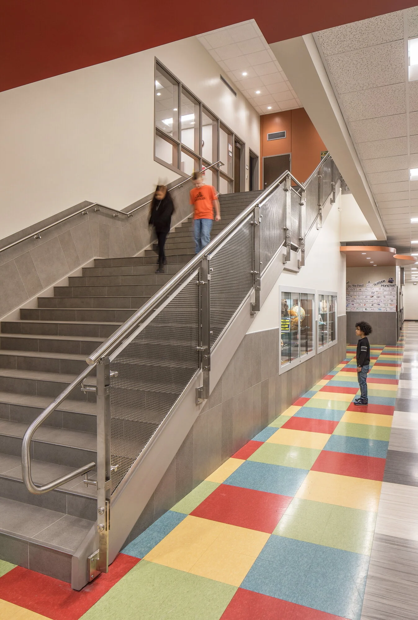Stairwell with a multicolored tile floor and orange wall