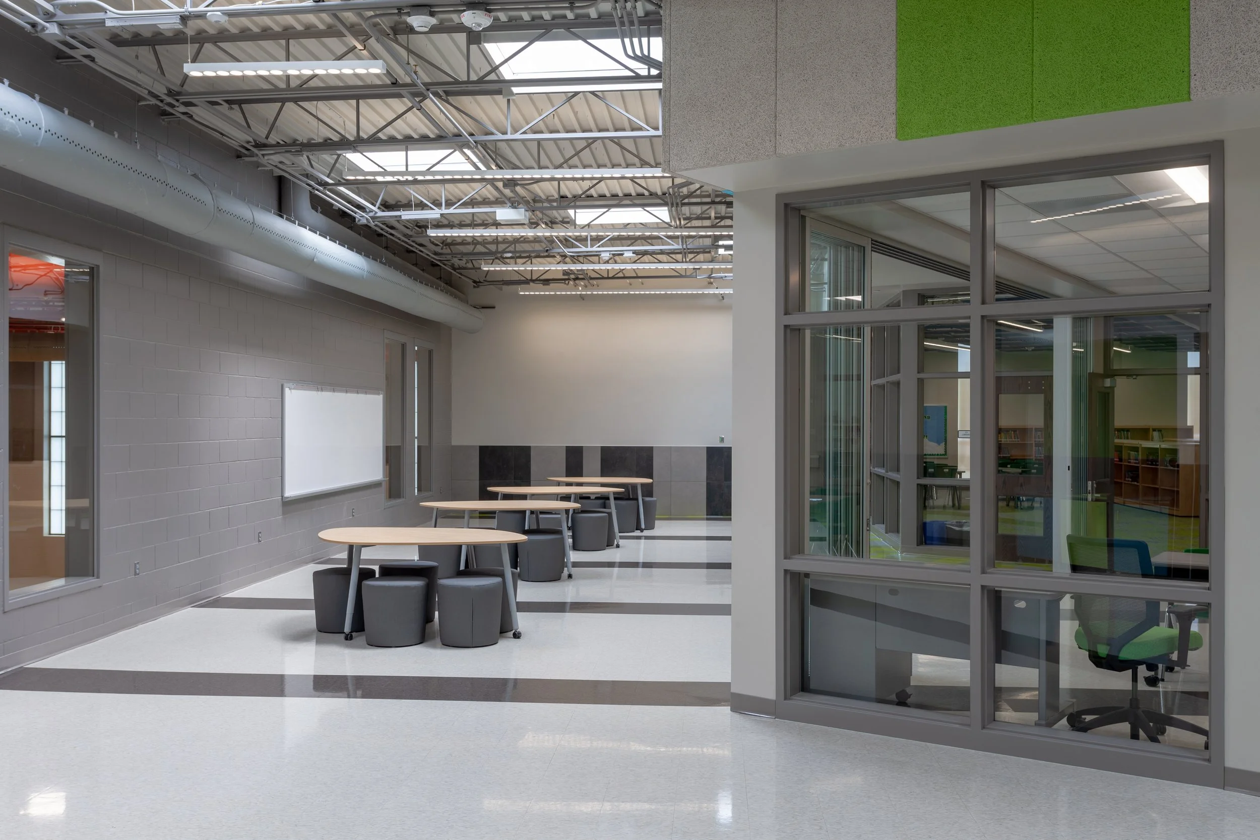 Collaboration space with glass-walled rooms and green accent panel