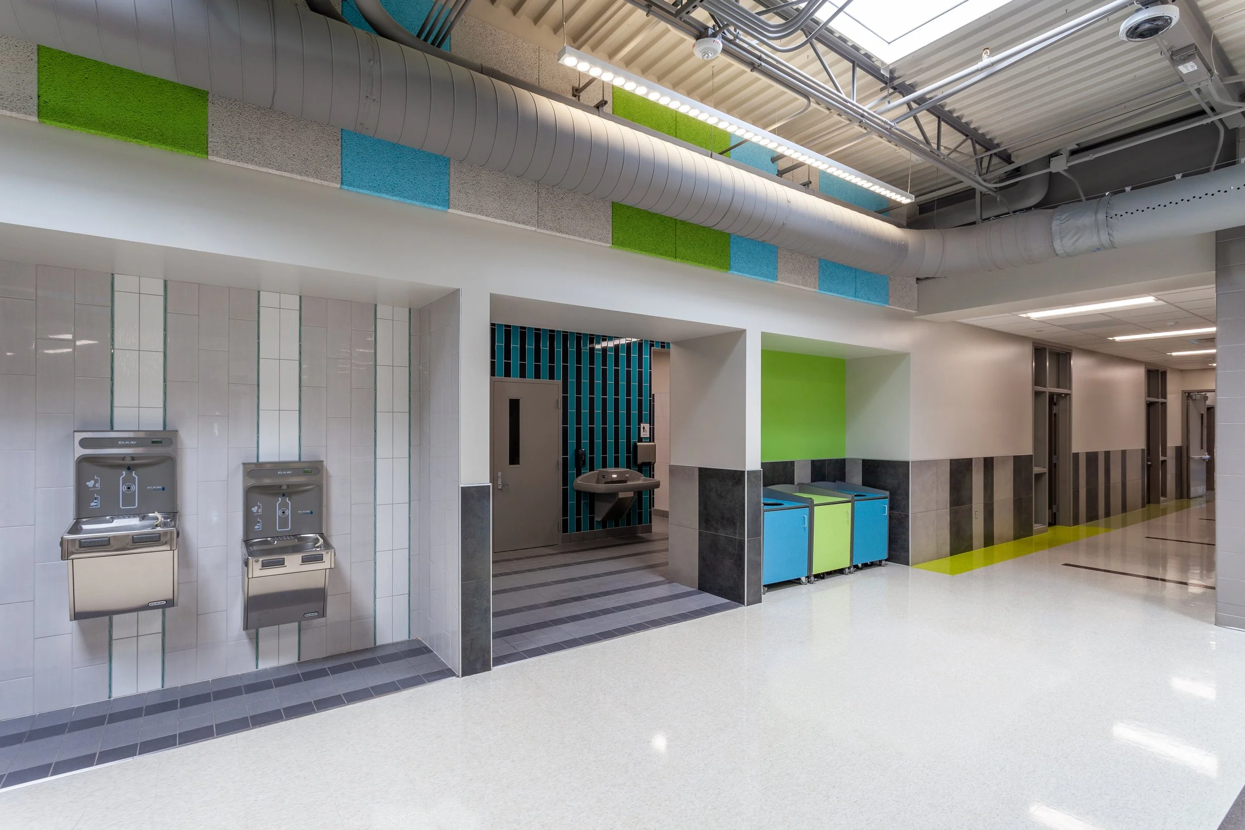 School corridor with lockers, colored wall accents and a drinking fountain