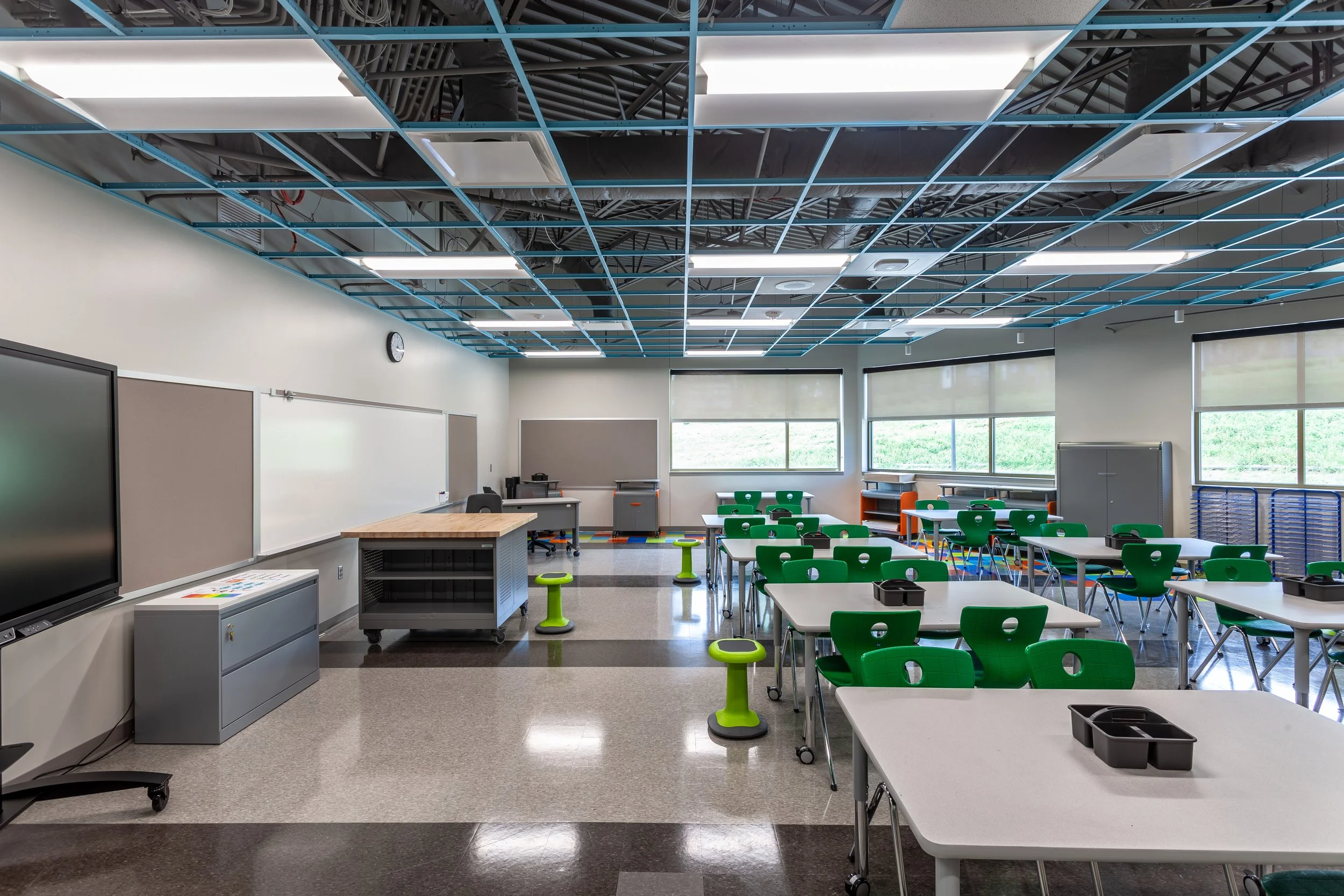 Classroom with green student chairs, mobile tables and a large display