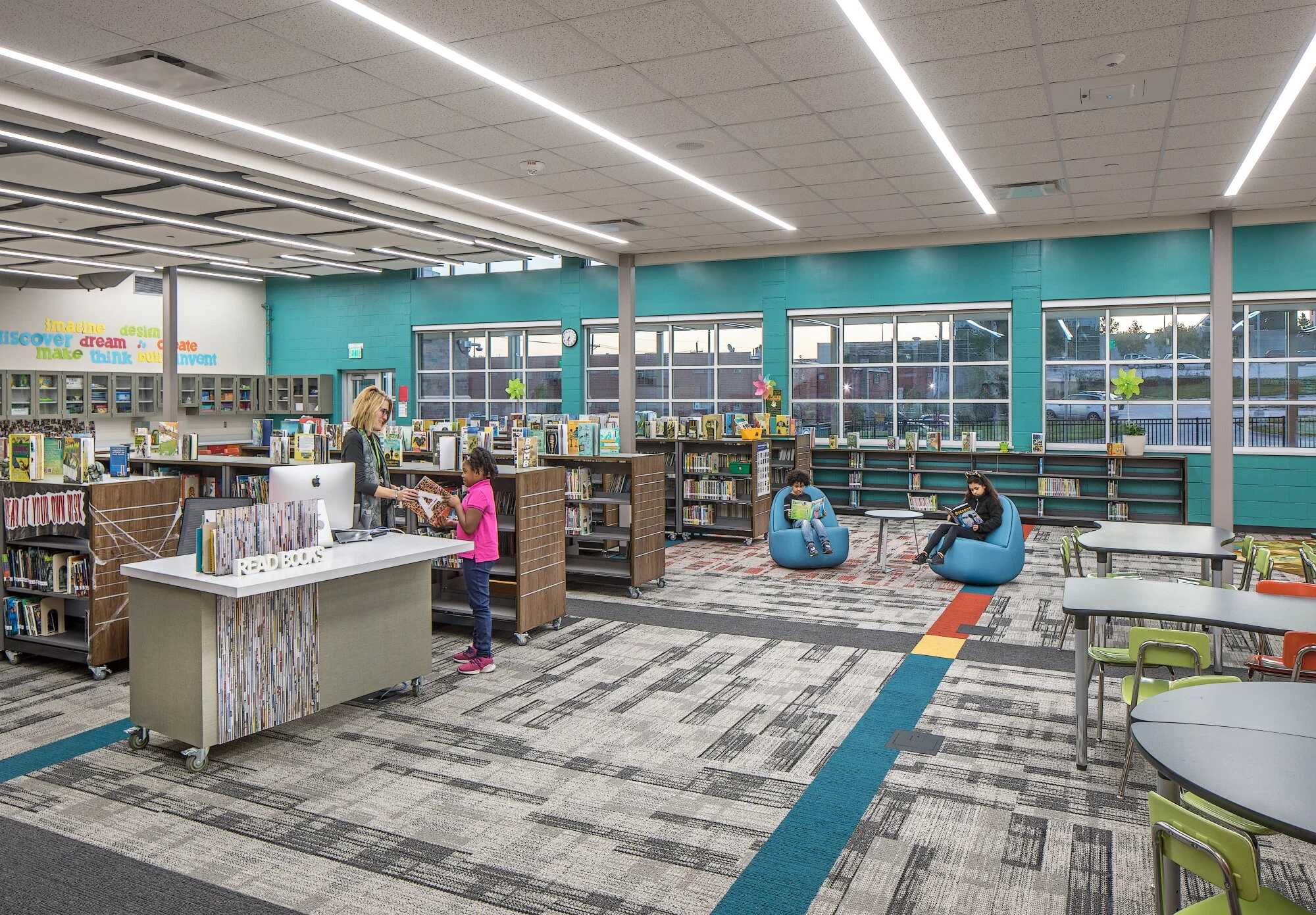 School library with teal walls, low shelving and bean bag chairs